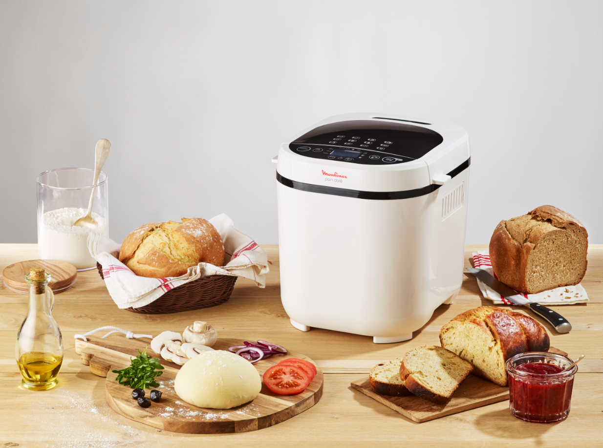 Broodmaakscène. Broodbakmachine op een houten tafel. Brood, bloem en andere ingrediënten zijn te zien.
