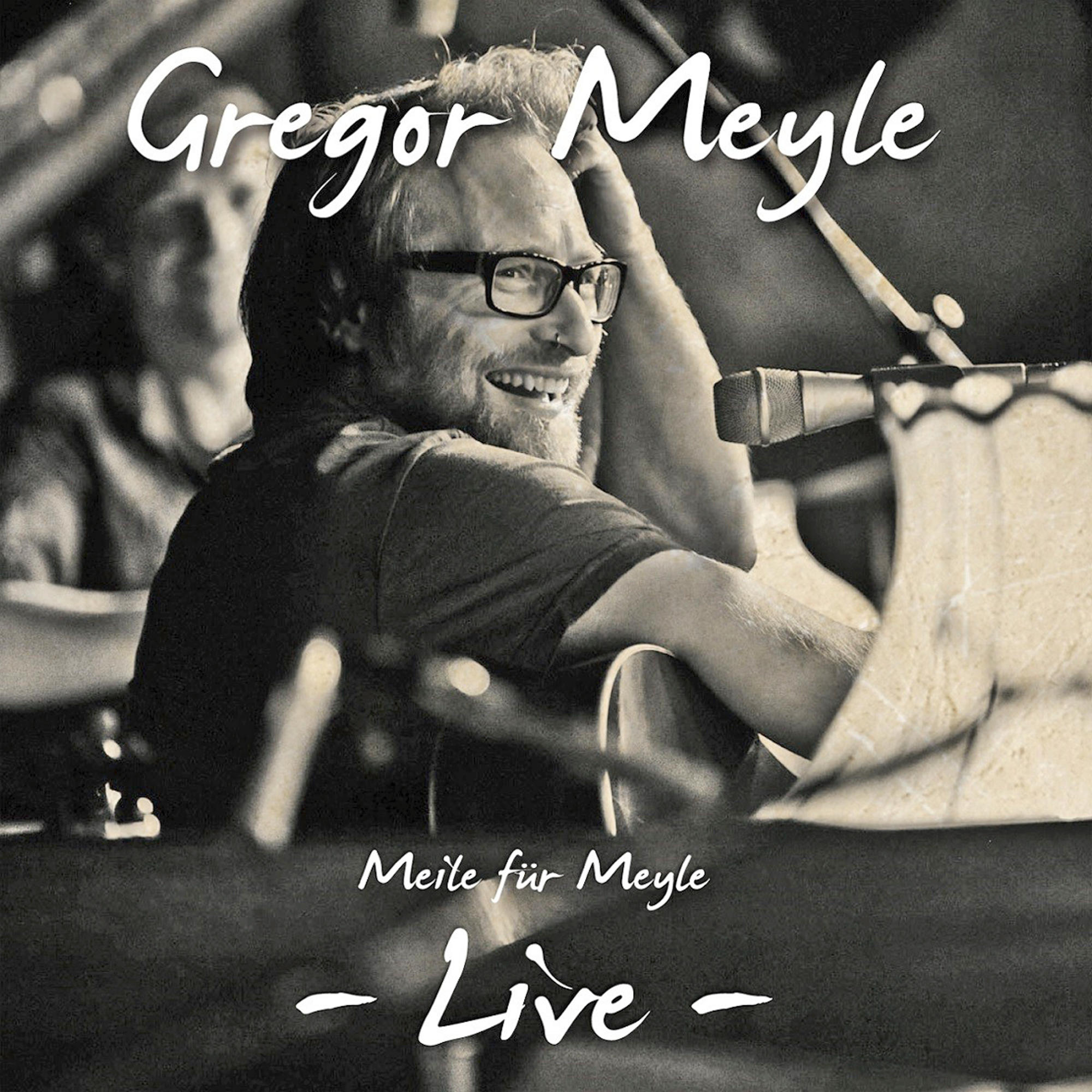 Albumcover mit einem lächelnden Mann mit Brille, der eine Gitarre hält.
