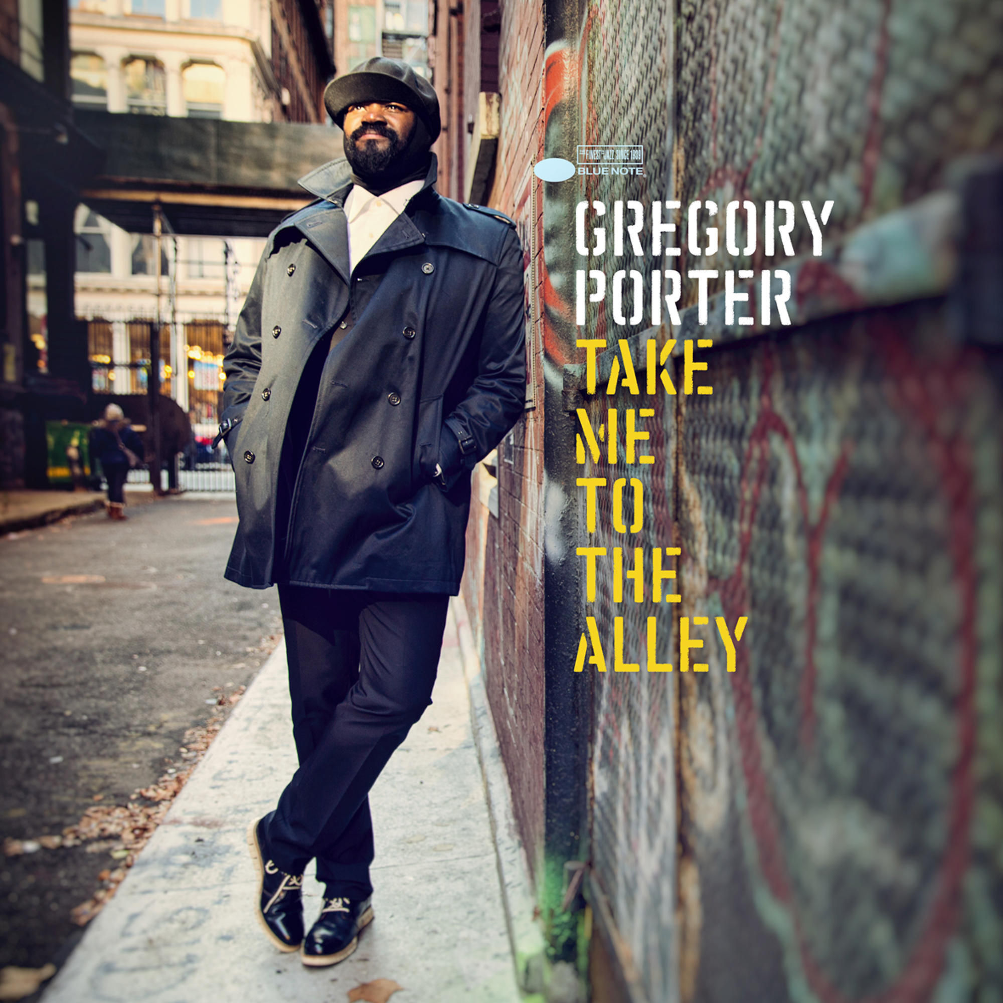 Mann in einem schwarzen Mantel lehnt an einer Wand mit Albumcover: Gregory Porter, Take Me To The Alley.
