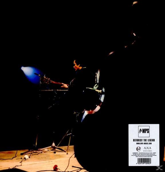 Dunkle Bühne mit einem Musiker, der ein Keyboard spielt, eine weiße Box mit Text unten rechts.