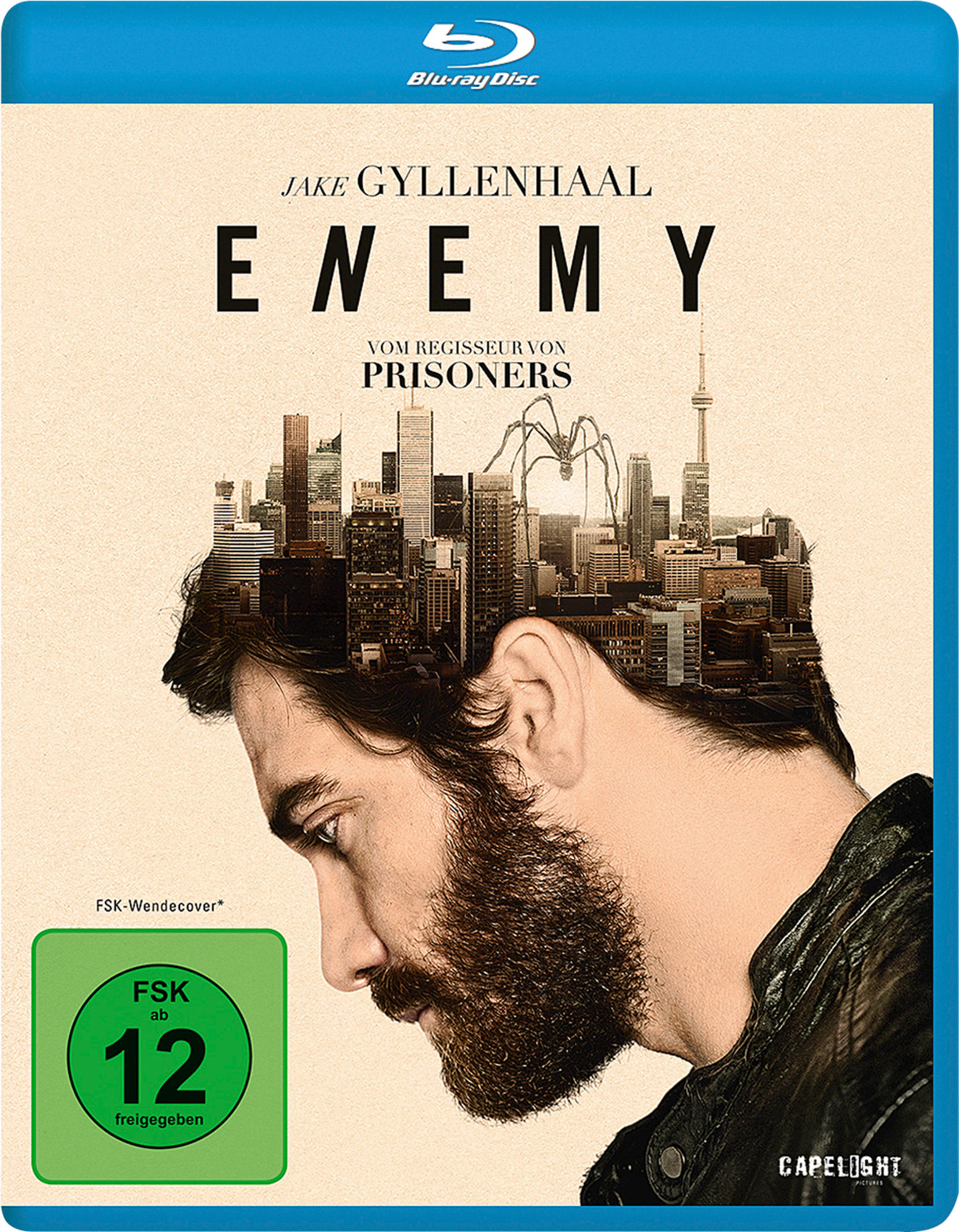 Blu-ray-Cover für Enemy. Jake Gyllenhaal mit Bart, nach unten schauend. Eine Stadt mit einer Spinne.
