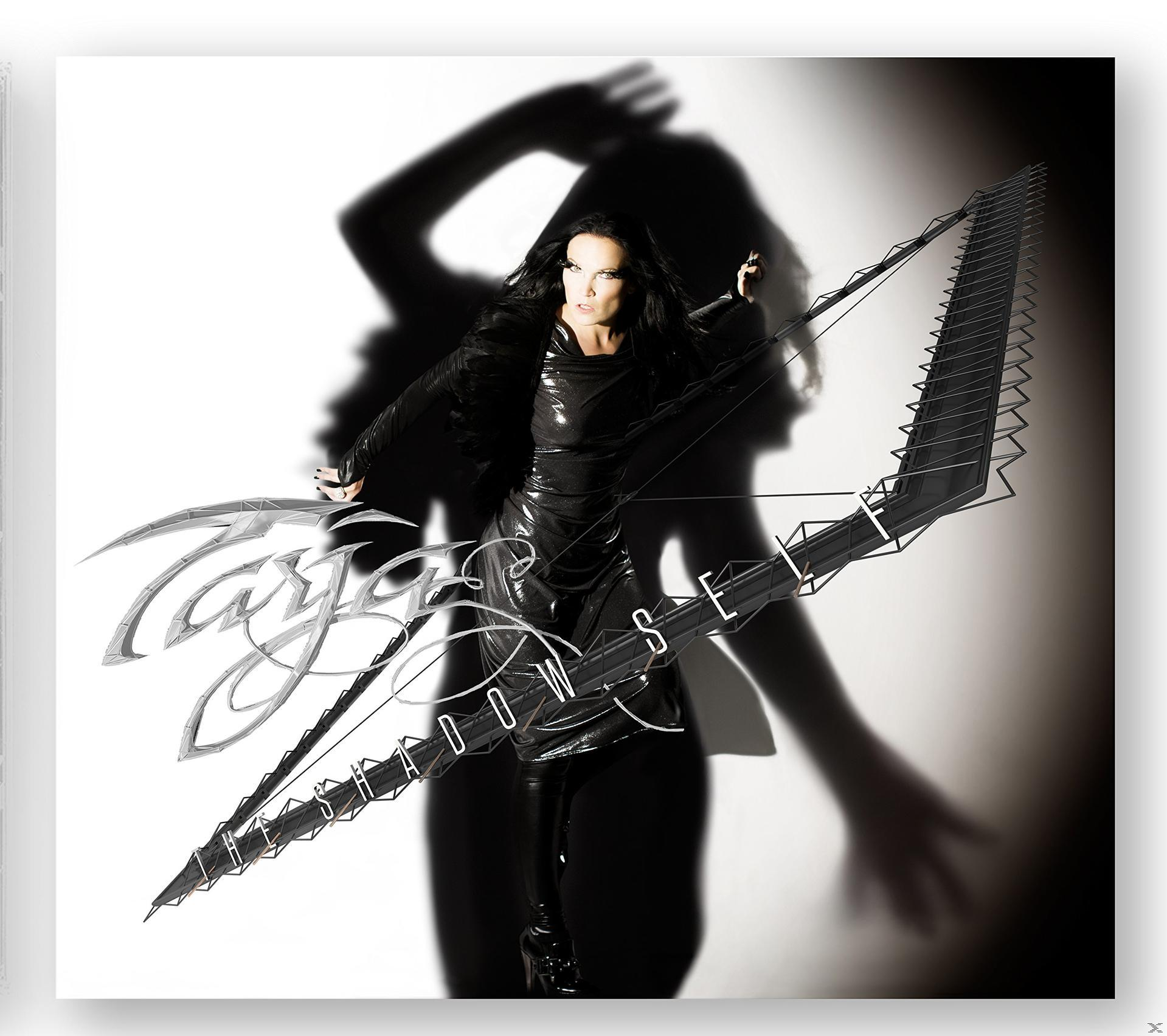 Eine Frau in schwarzer Kleidung mit einem Bogen. Text: Tarja Shadow Self.