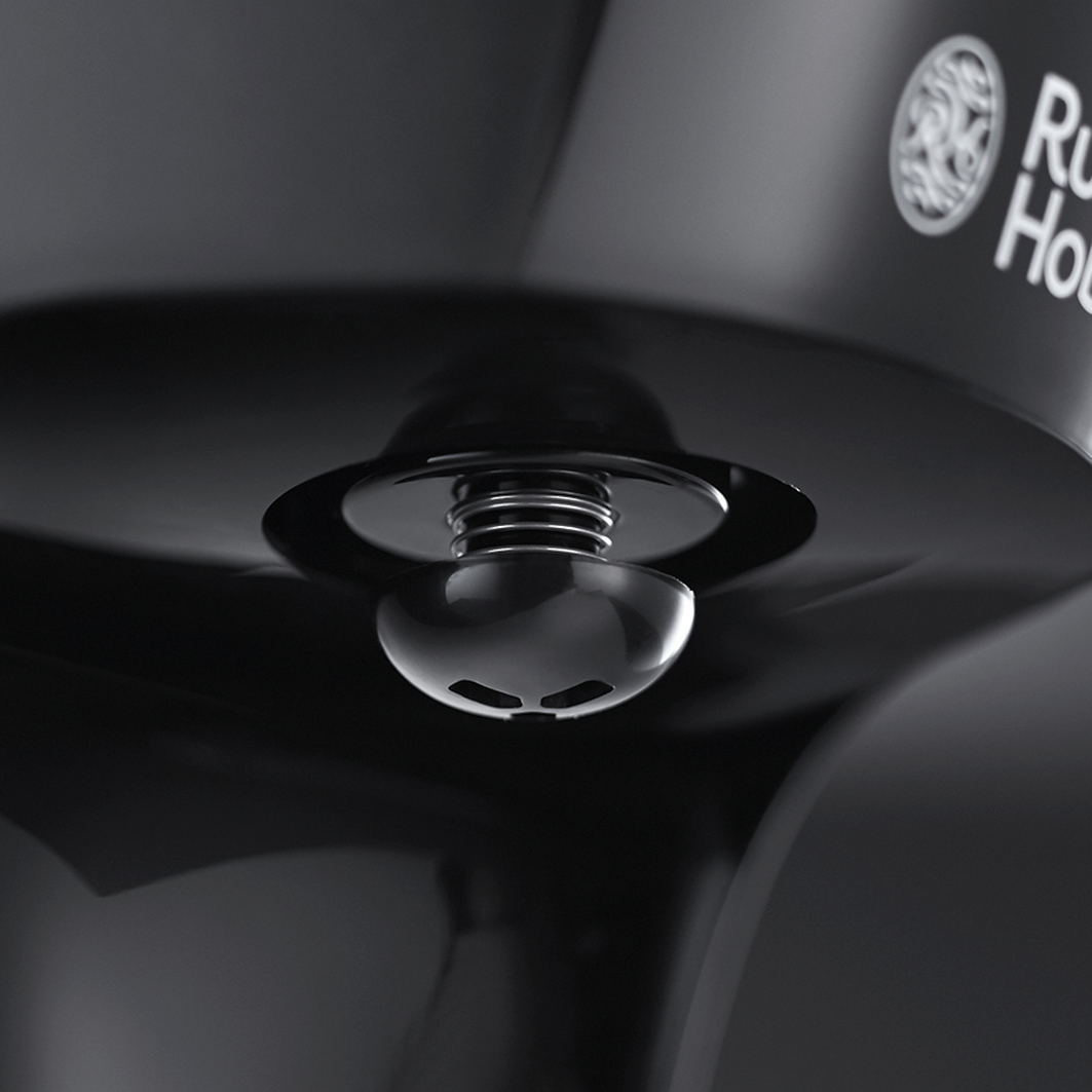 Close-up of a black appliance with a button and metallic coil.