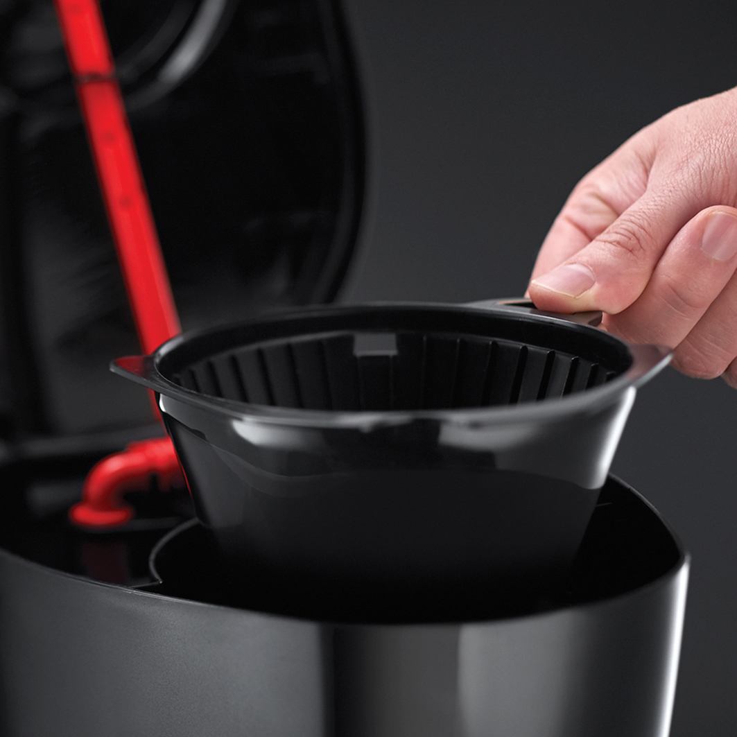 Close-up of a black coffee maker filter basket being inserted into the machine.