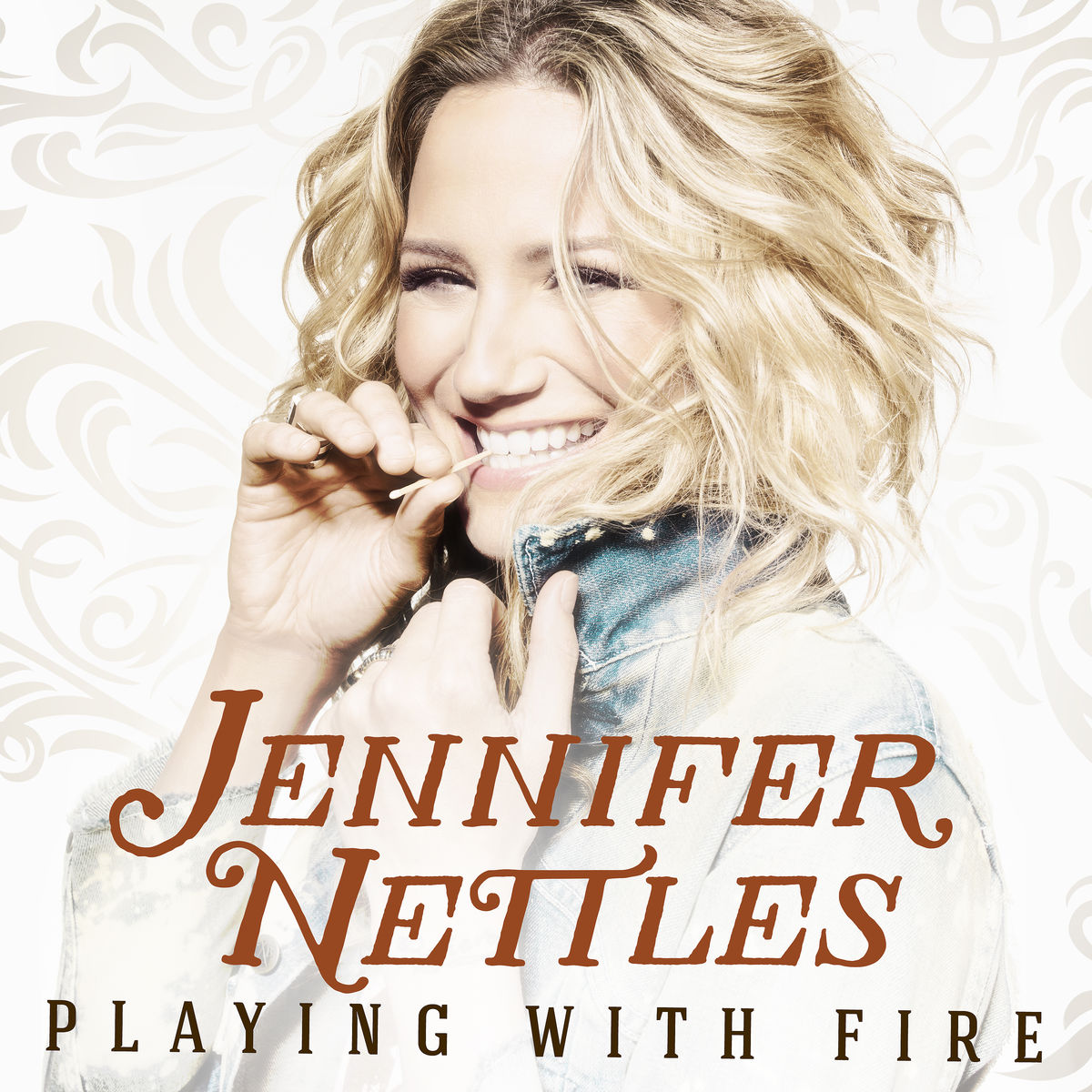 Jennifer Nettles Albumcover. Frau lächelt, Zahnstocher im Mund. Titel: Playing With Fire.