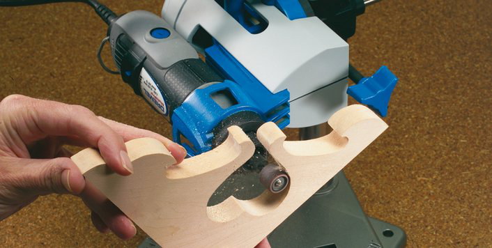 Kéz Dremel szerszámot használ fából készült tárgy formázásához a munkaasztalon.