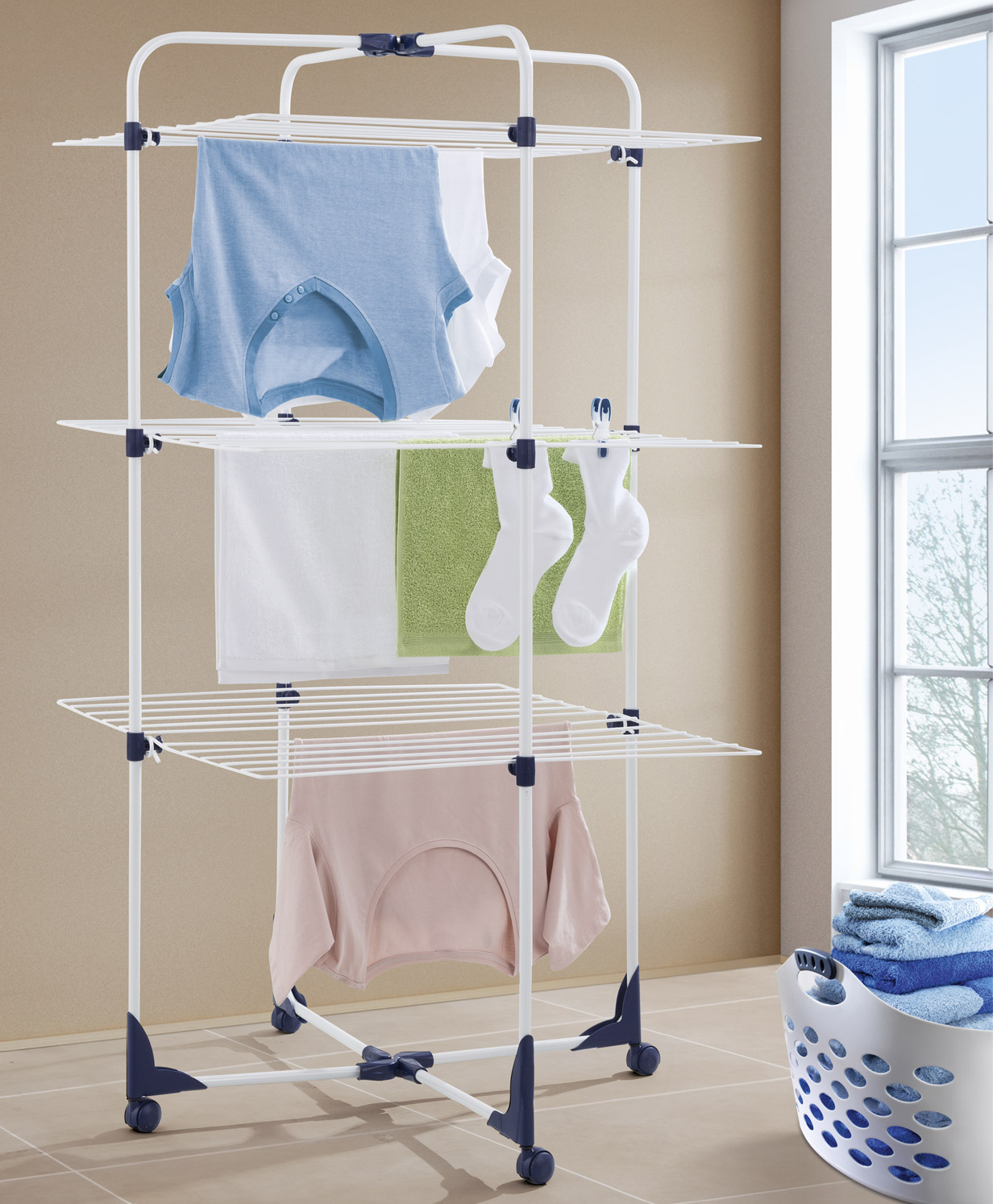 Weißer Wäscheständer mit hängender Kleidung, in der Nähe eines Fensters.