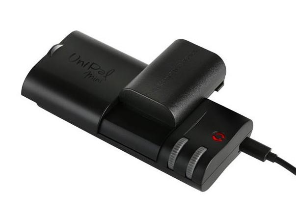 Schwarzes Kamera-Akkuladegerät mit eingelegtem Akku und rotem Licht.