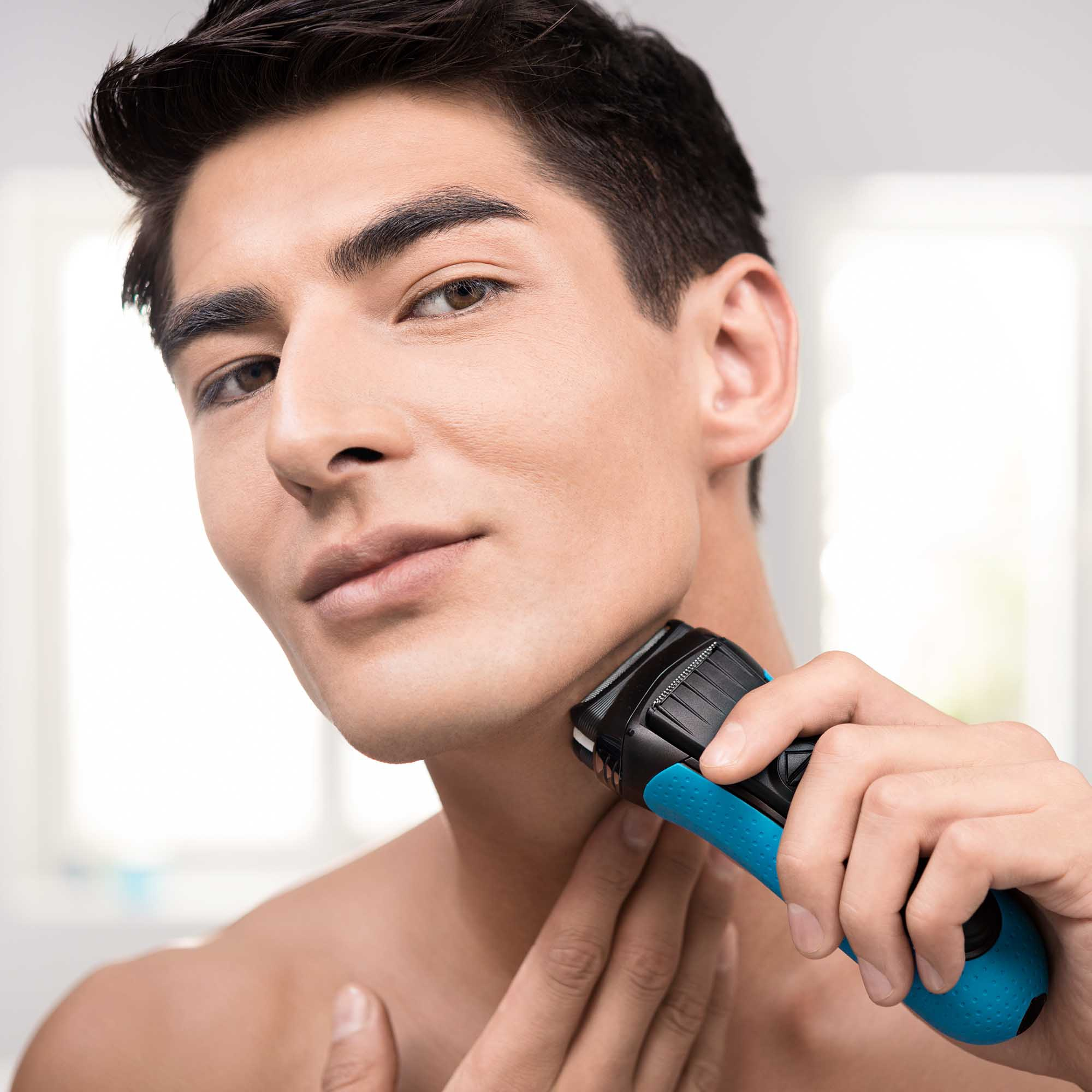 Un uomo che si rade il collo con un rasoio elettrico, primo piano.