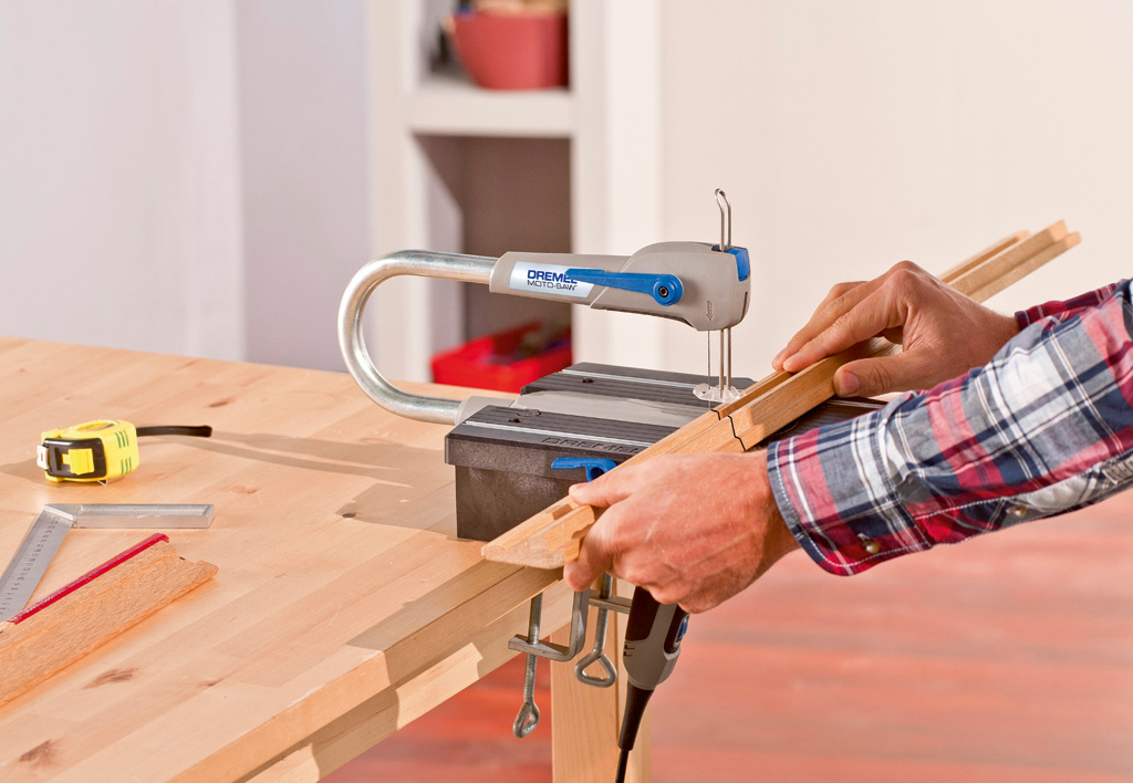 Személy egy Dremel Moto-Saw-t használva fát vág egy asztalon.