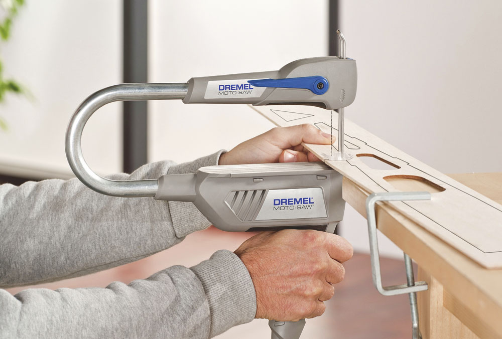 Egy személy Dremel Moto-Saw-t használ fát vágni. A fűrész szürke és kék.