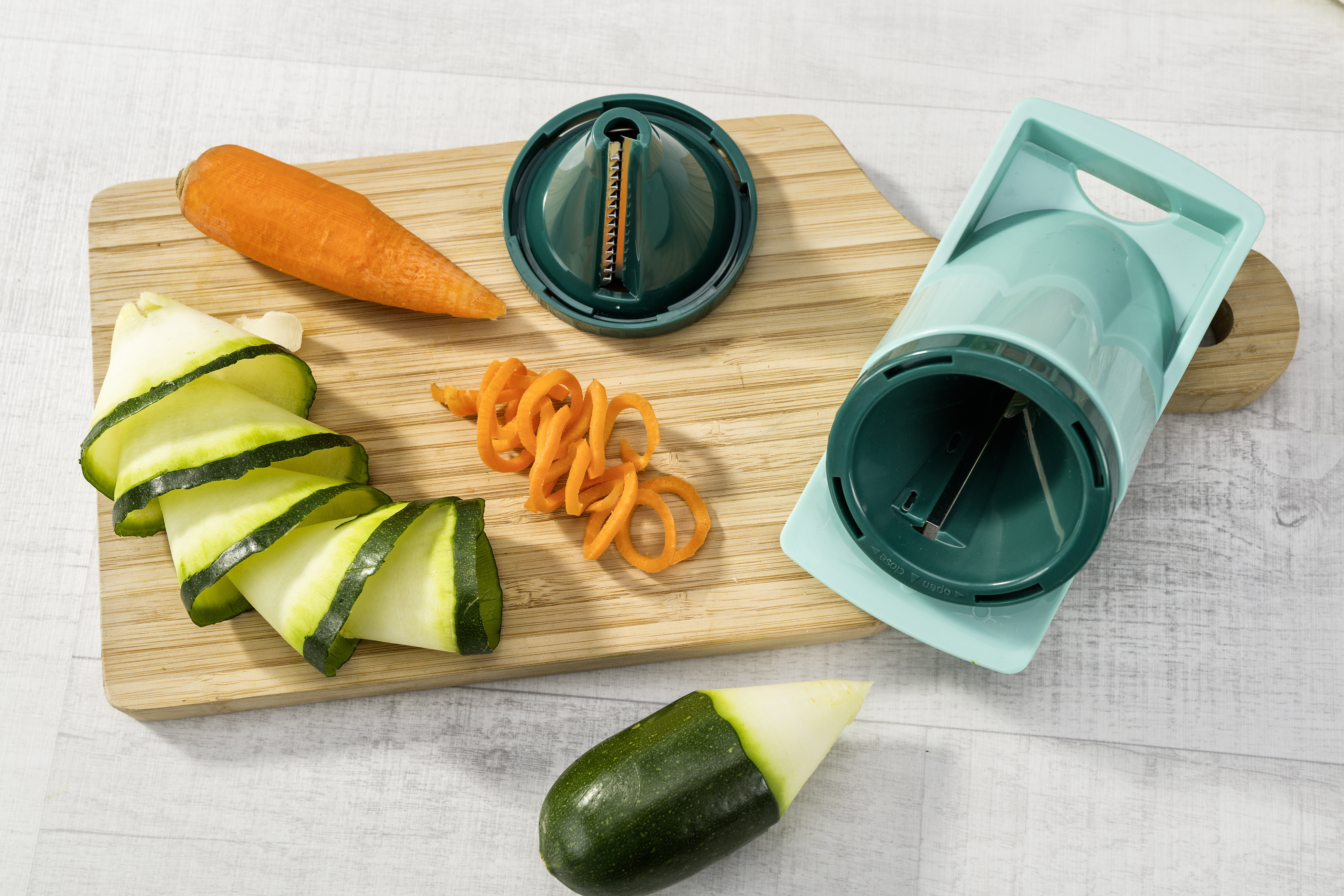 Gemüsespiralizer und frische Spiralen aus Zucchini, Karotten und weißem Rettich.