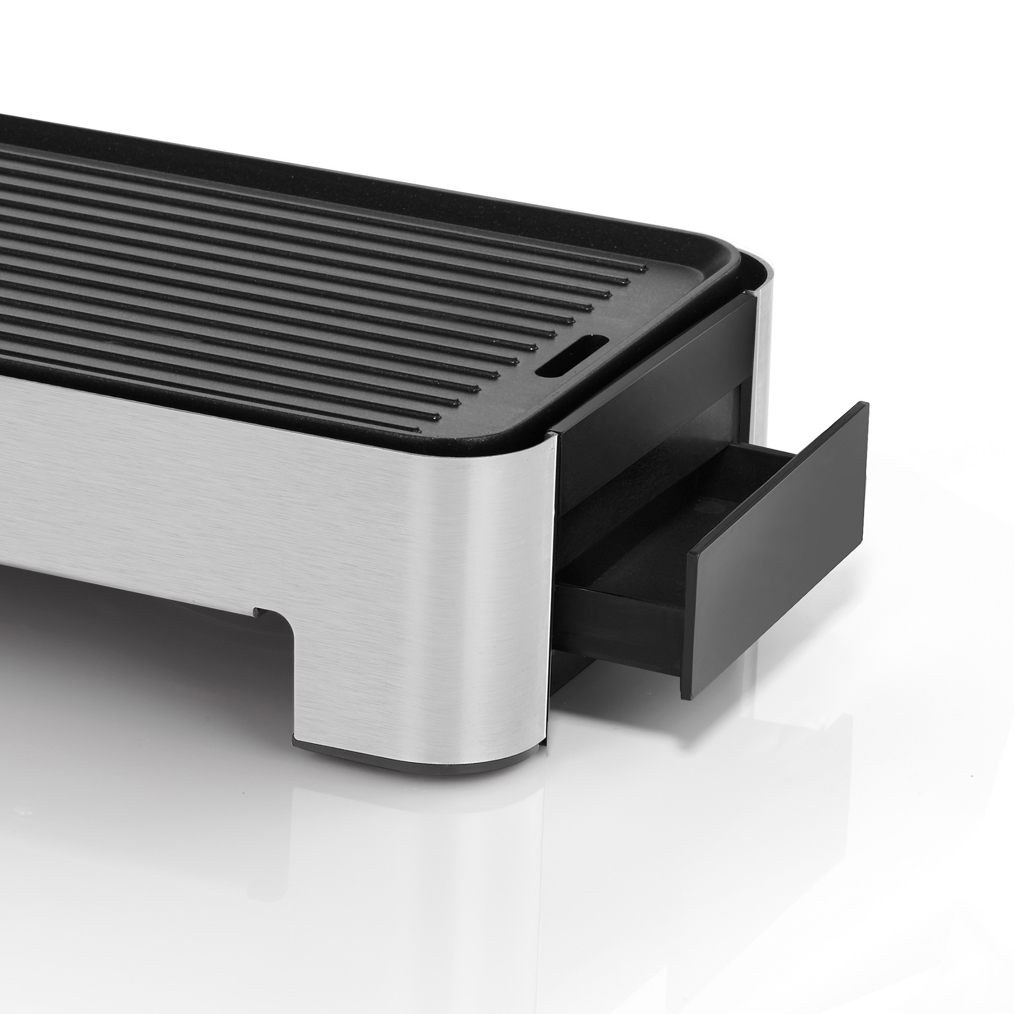 Gril argenté et noir avec un tiroir sorti. Il est sur une surface blanche.