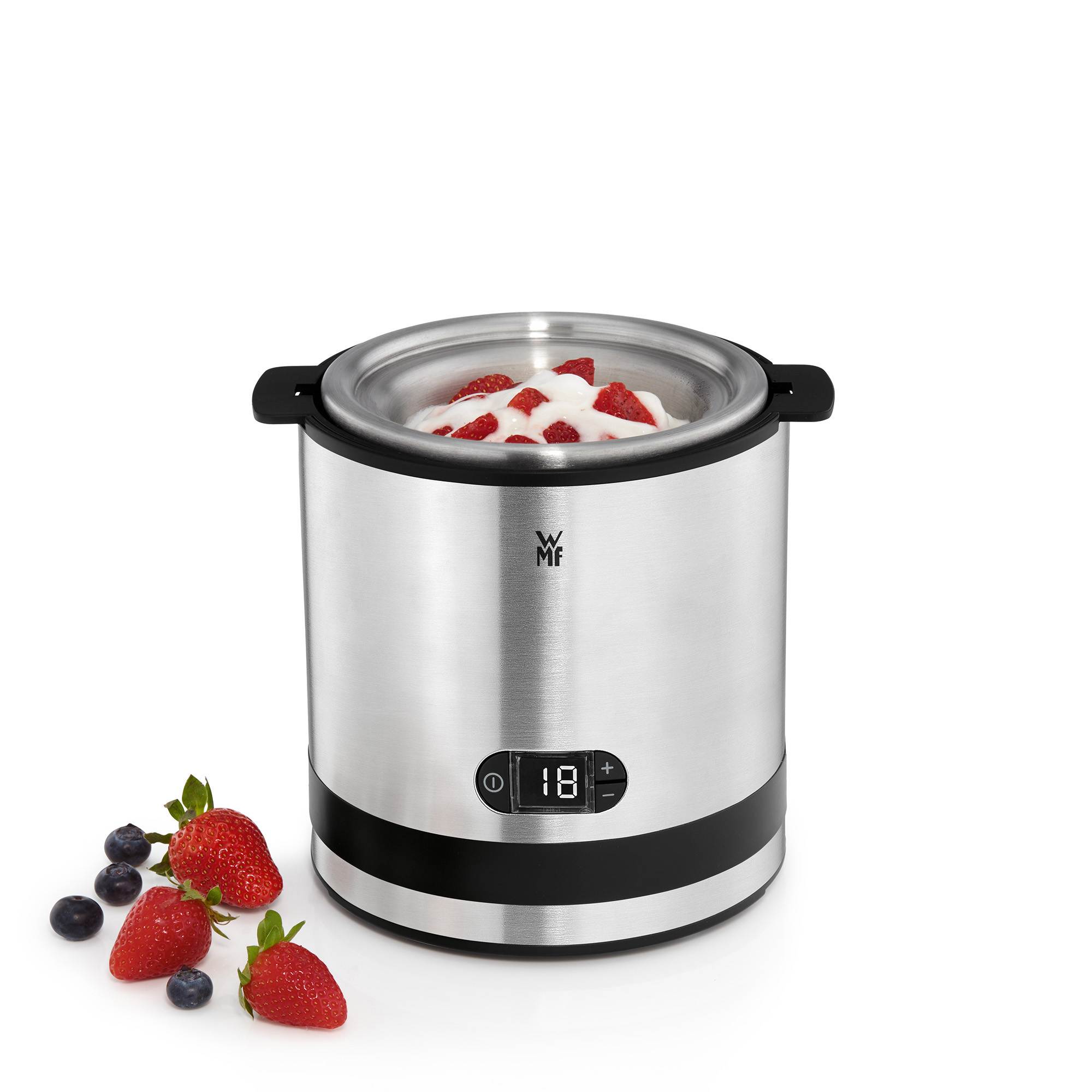 Eine silberne Eismaschine mit Erdbeeren und Blaubeeren auf dem Tisch.