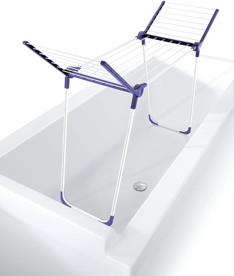 Weiße Badewanne mit einem lila-weißen Wäscheständer. Weißer Hintergrund.