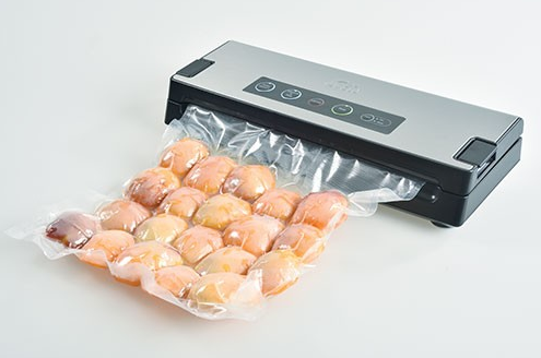 Scelleuse sous vide avec un sac d'aliments précuits, scellés, de couleur orange.