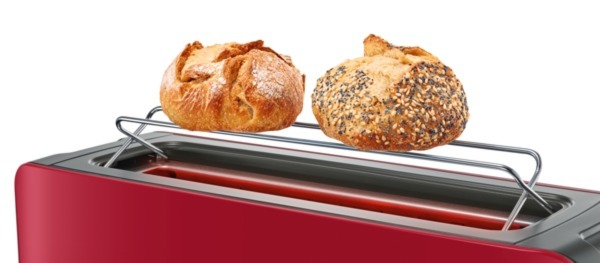 Toaster mit zwei Brötchen oben drauf. Roter Toaster. Brötchen sind braun mit Samen.