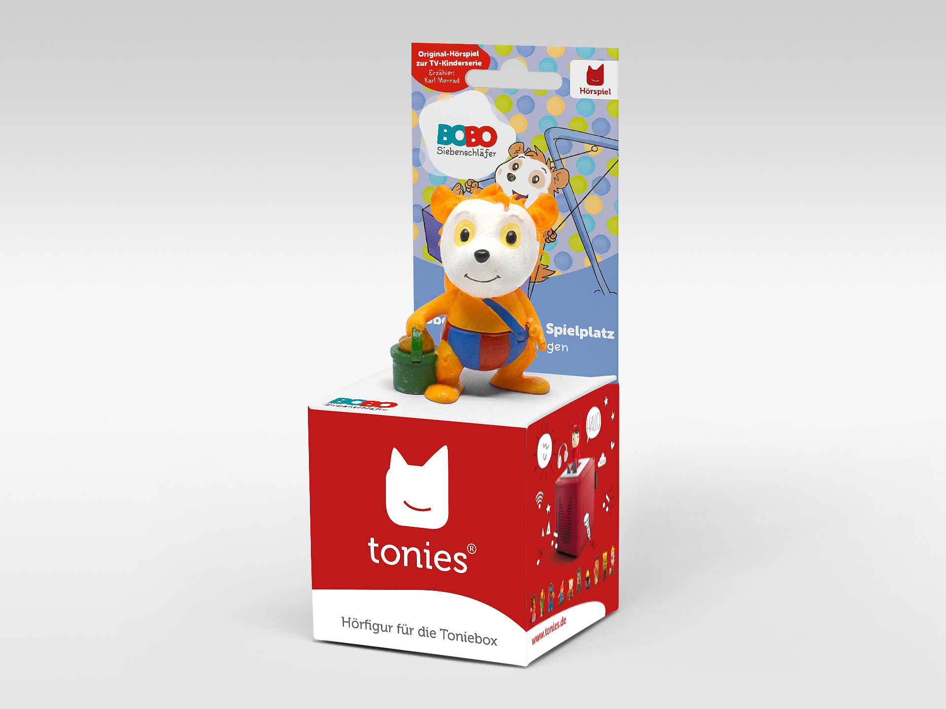 Eine Spielfigur auf einer Box mit einem Spielplatz. Die Box hat den Markennamen 'tonies' und eine rote Farbe.