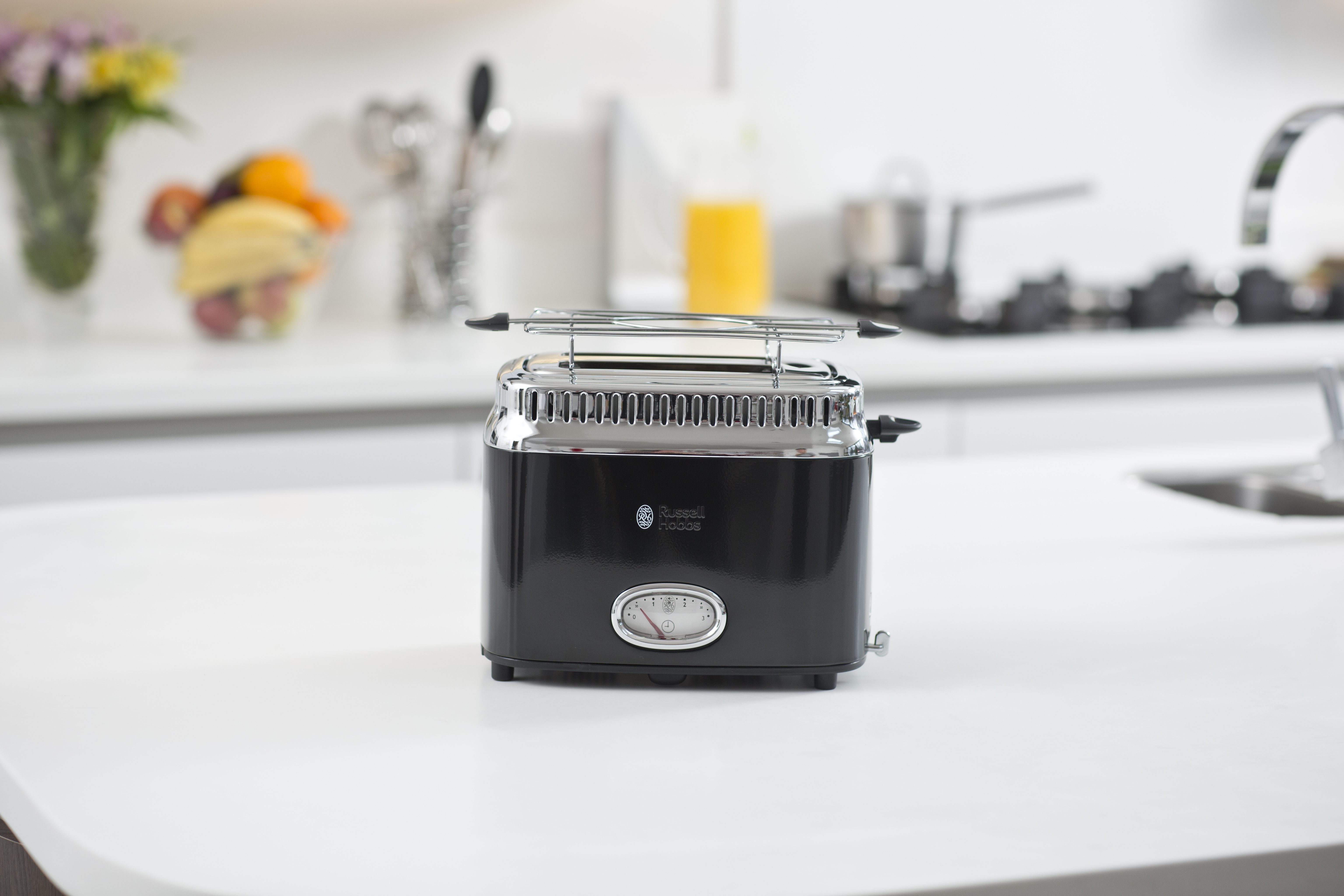 A black and silver toaster sitting on a white countertop in a kitchen.