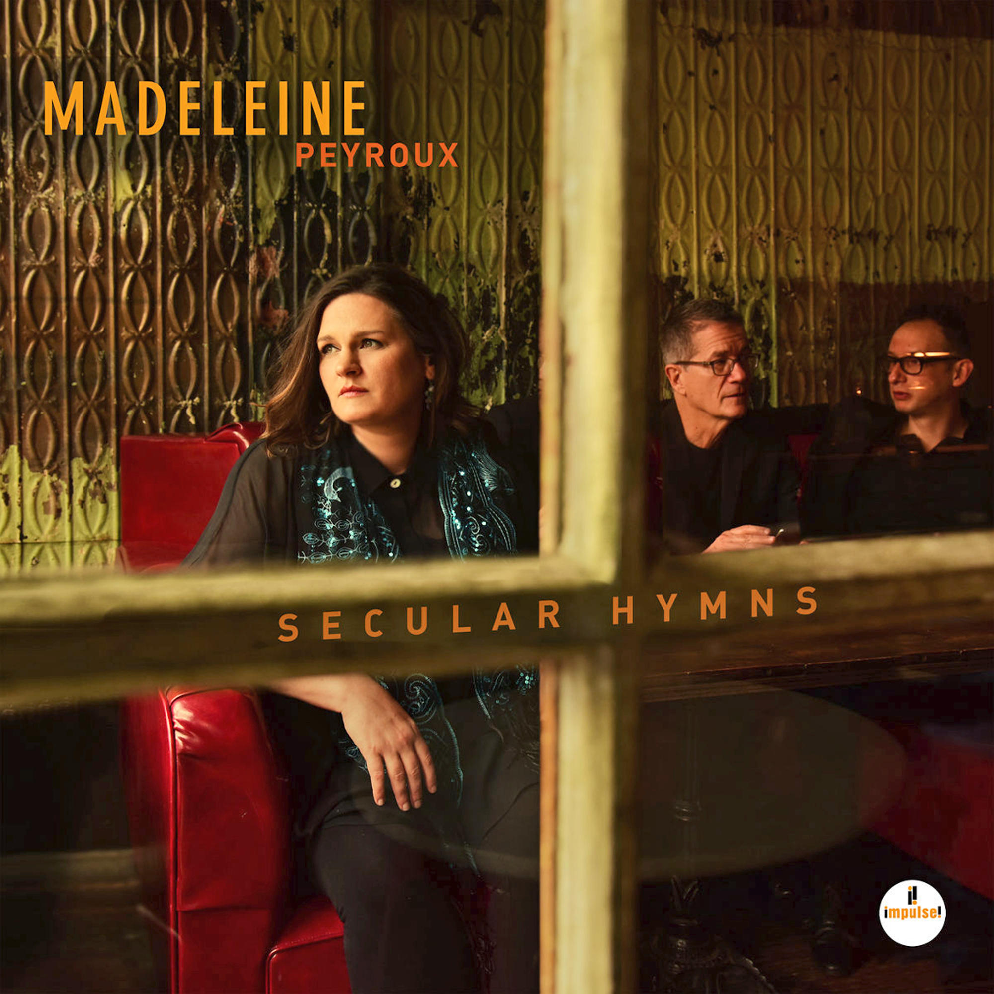 Albumcover von Madeleine Peyroux. Sie sitzt in einer roten Kabine. Der Albumtitel lautet Secular Hymns.