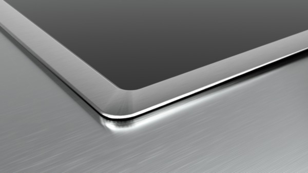 Nahaufnahme einer metallischen Oberfläche. Die Oberfläche ist gebürstetes Metall mit glänzendem Rand.