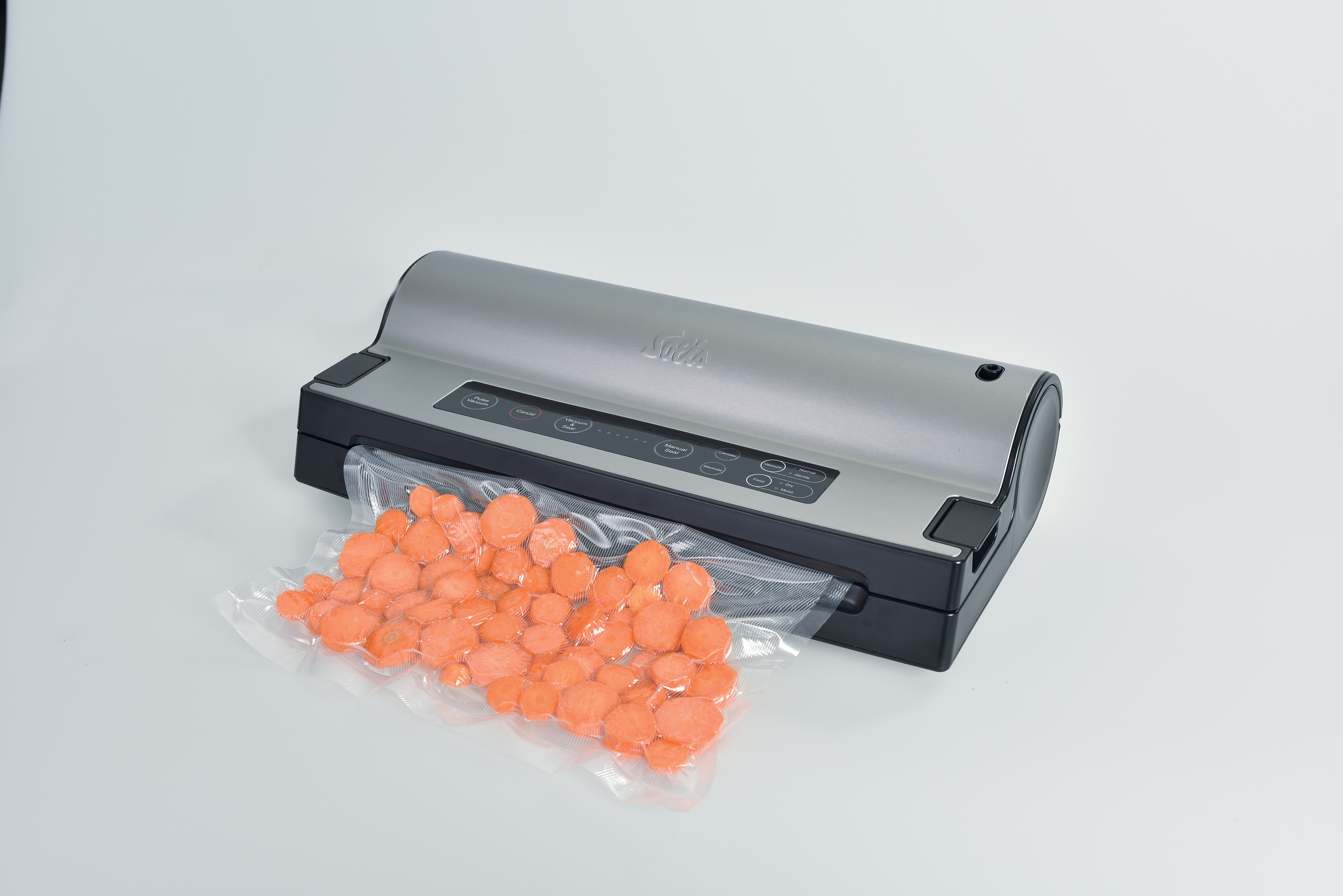 Een zilveren voedselvacumeermachine met een zakje gesneden oranje wortelen.
