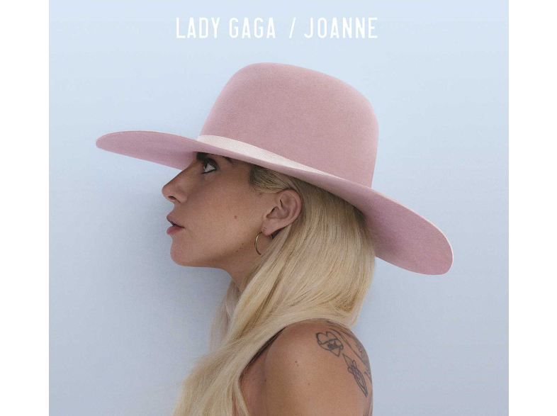 Lady Gaga profilból, rózsaszín kalapot, szőke hajat visel, világoskék háttérrel.