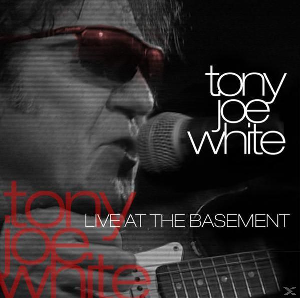 Tony Joe White, Live at the Basement. Ein Mann mit Sonnenbrille singt in ein Mikrofon und spielt Gitarre.
