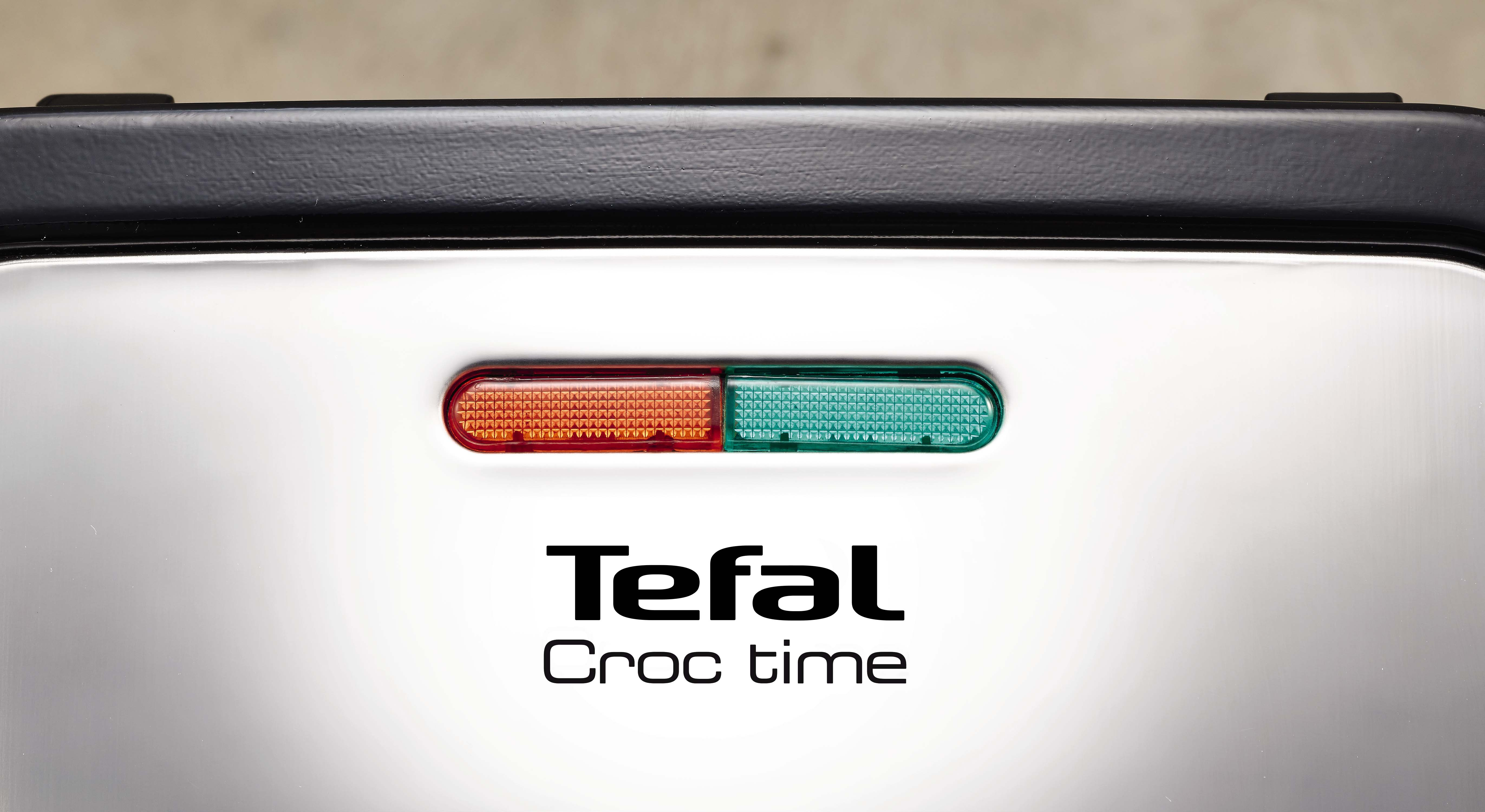 Tefal Croc time waffle maker with red and green indicator lights on a silver surface.