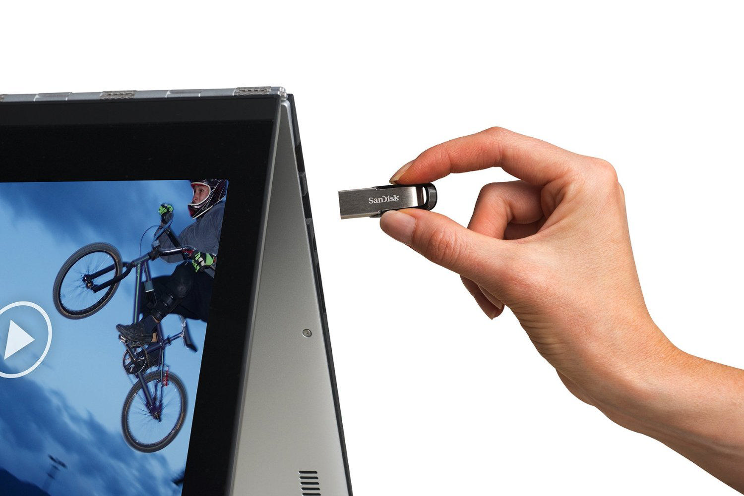 El, bir motosikletçinin olduğu dizüstü bilgisayar ekranının yanında gümüş USB sürücü tutuyor.
