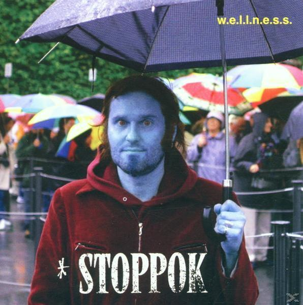 Ein Mann mit blauem Gesicht unter einem Schirm. Rote Jacke, grüner Hintergrund und andere Leute im Regen.