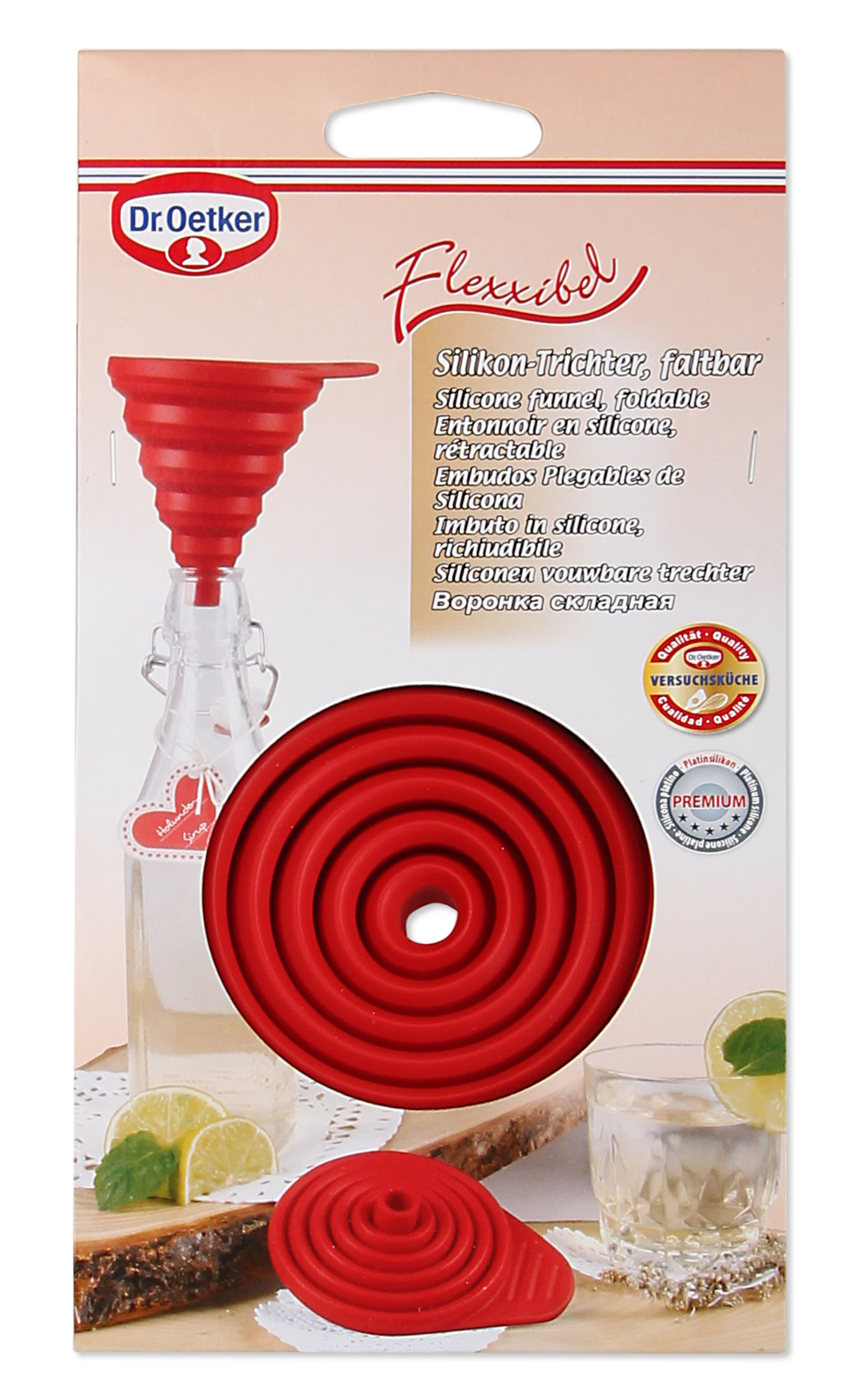 Roter Silikontrichter, flach gefaltet, neben einer Glasflasche und einem Glas mit Limette.