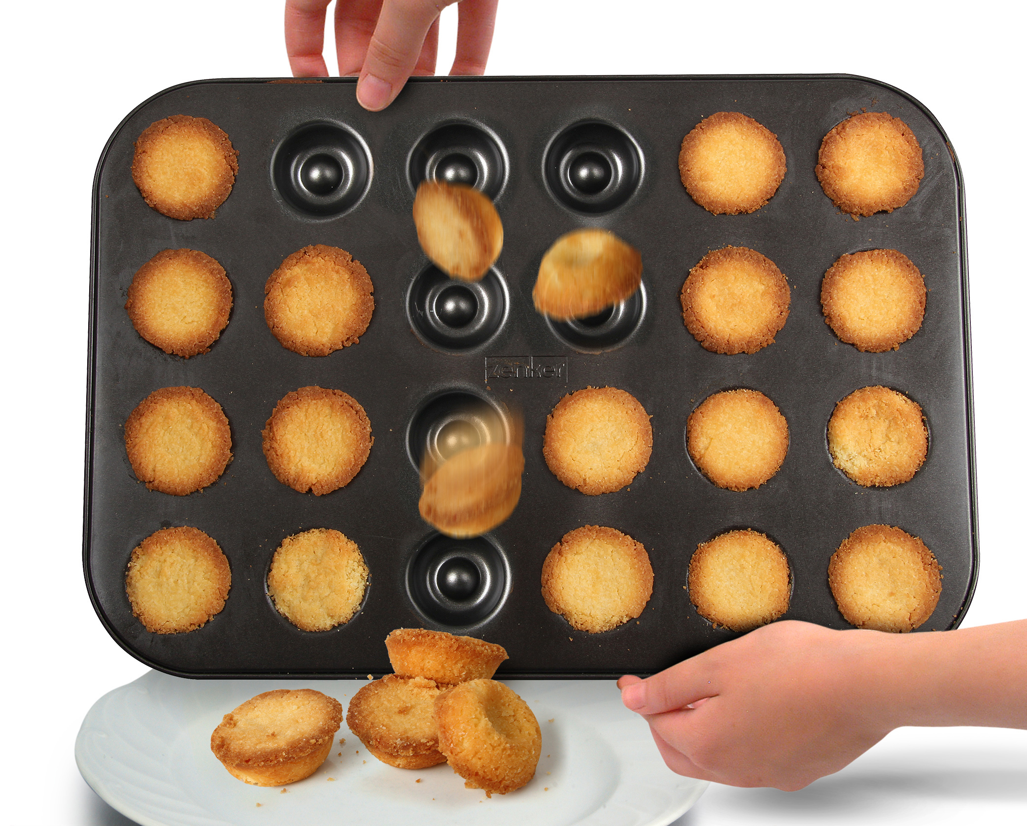 Muffinform mit Backwaren. Einige Muffins fallen aus der Form auf einen weißen Teller.