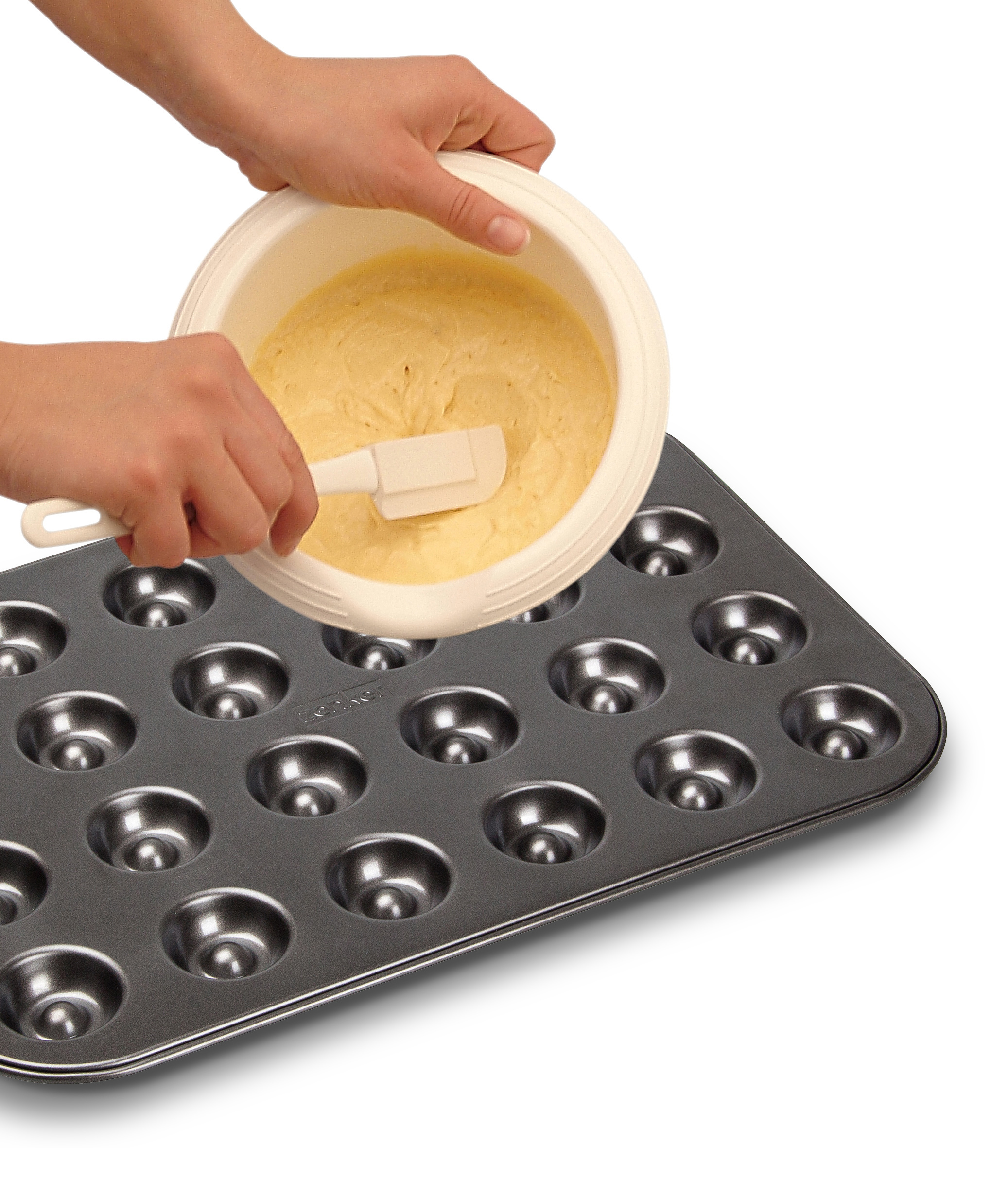Hände gießen Teig in eine Muffinform, weißer Hintergrund.