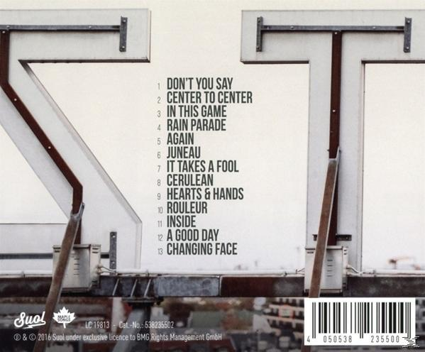 Album-Rückseite mit Titelliste vor einem Gebäude.