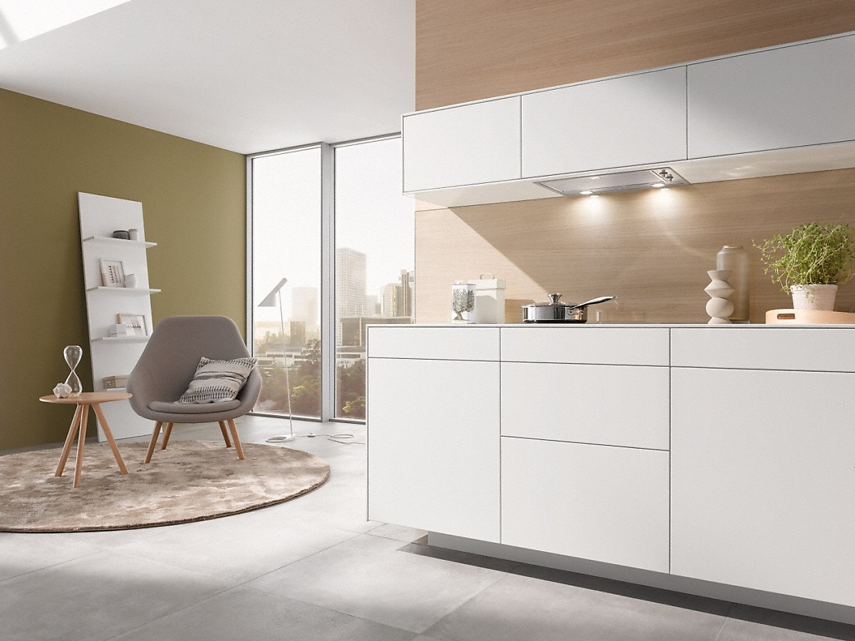 Modernes weißes Kücheninterieur. Mit weißen Schränken, einem Fenster und einer Holzakzentwand.
