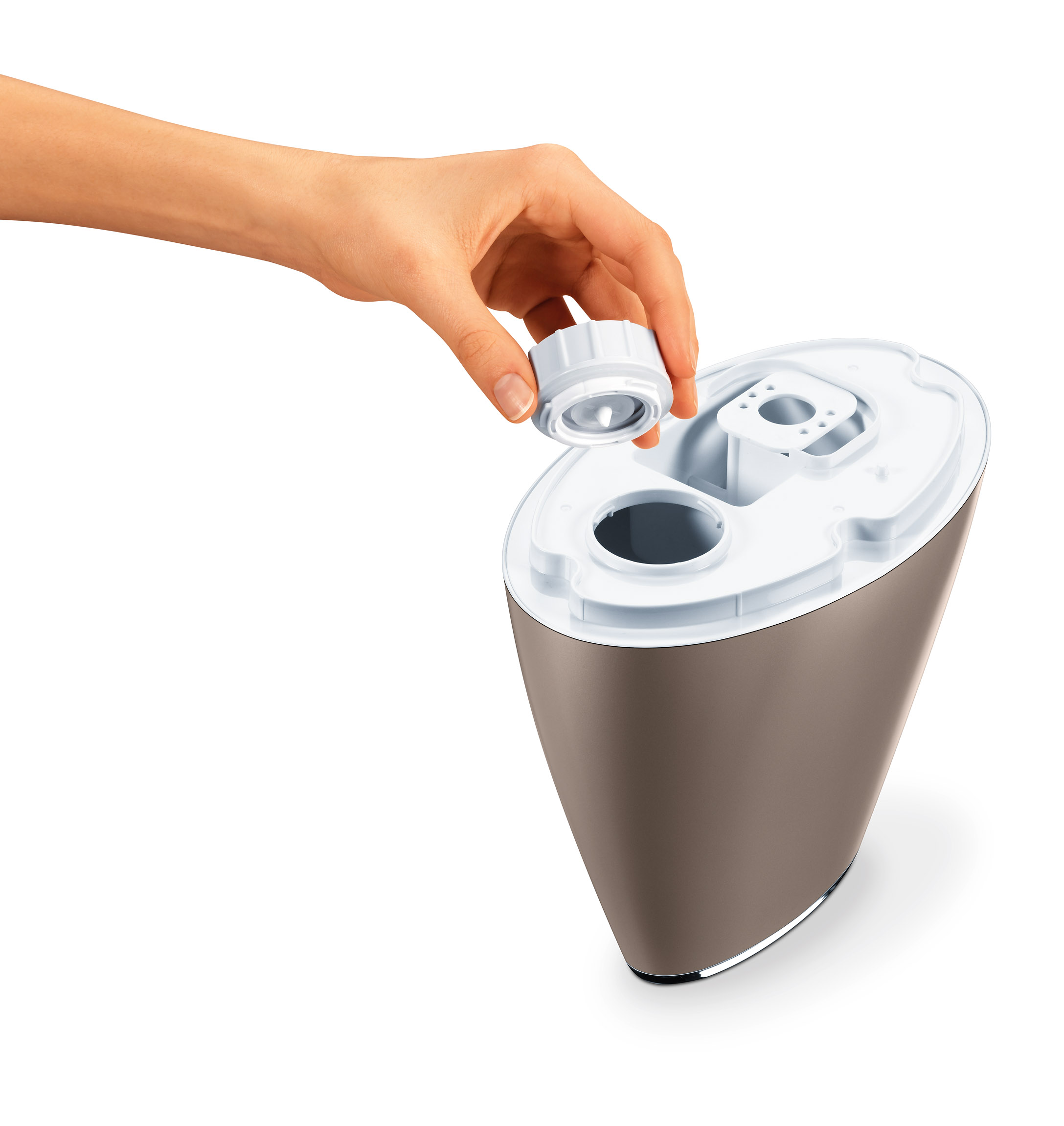 Una mano tiene il coperchio di un umidificatore, l'interno è visibile. Colore marrone e bianco.