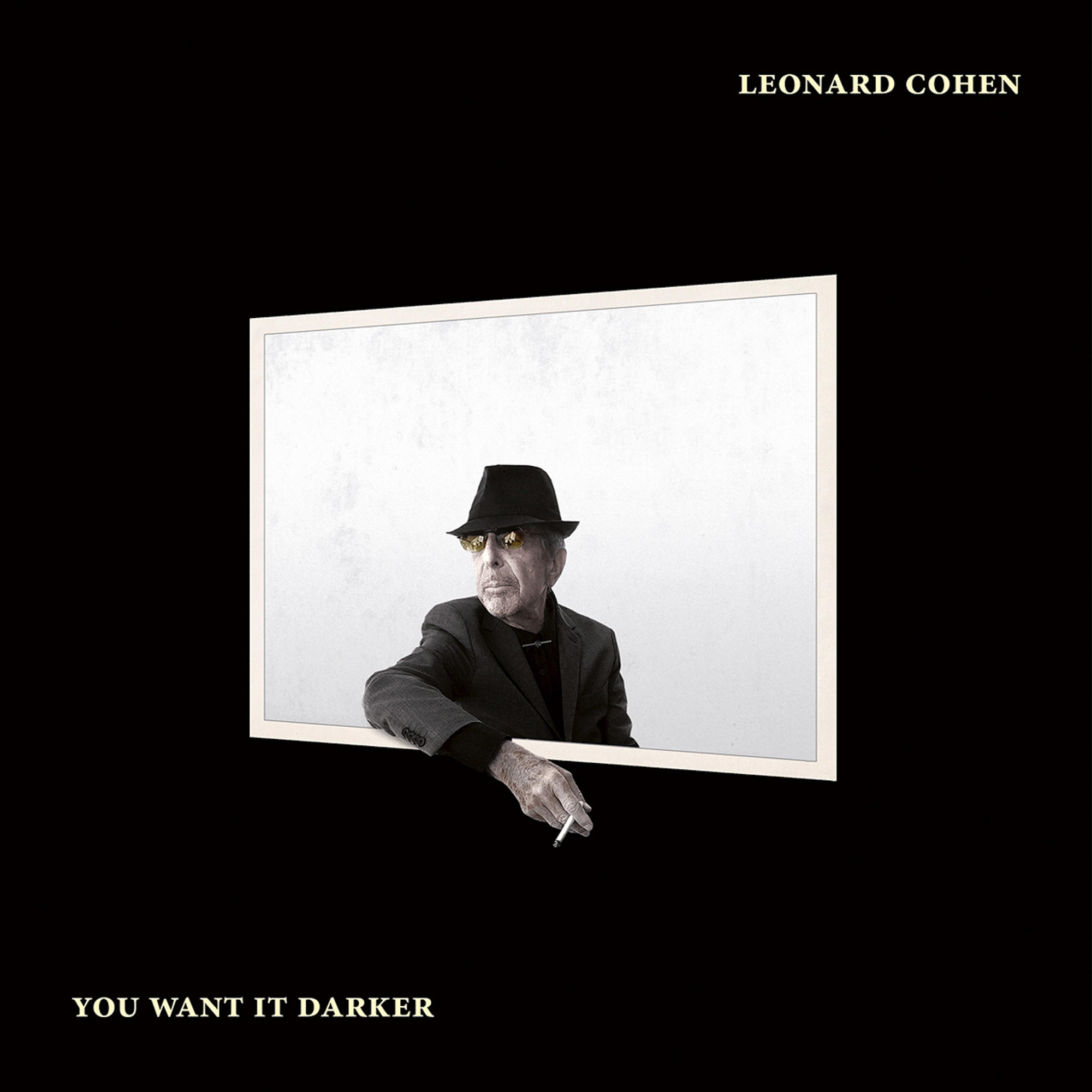 Albumcover. Leonard Cohen mit Hut und Brille, lehnt an einem Rahmen. Titel: You Want It Darker. Schwarzer Hintergrund.