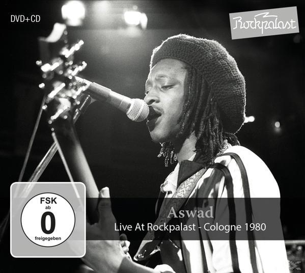 Aswad auf der Bühne, Gitarre spielend, in ein Mikrofon singend, Schwarzweißfoto. Text: Live At Rockpalast, Köln 1980.
