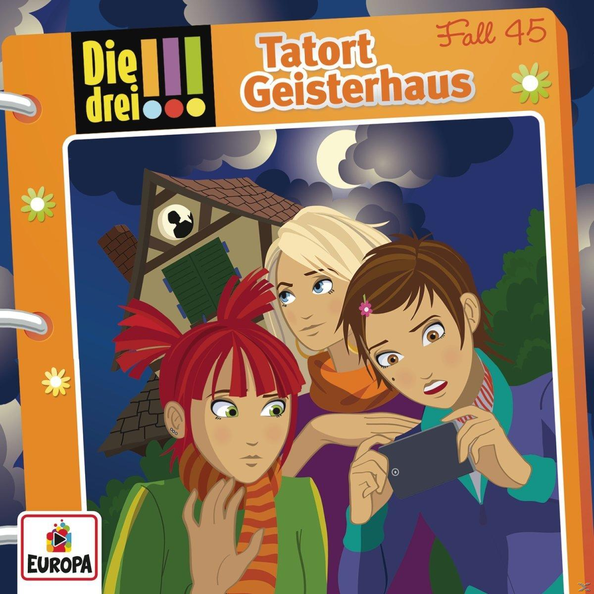 Drei Mädchen schauen überrascht auf ein Handy, ein Geisterhaus im Hintergrund.