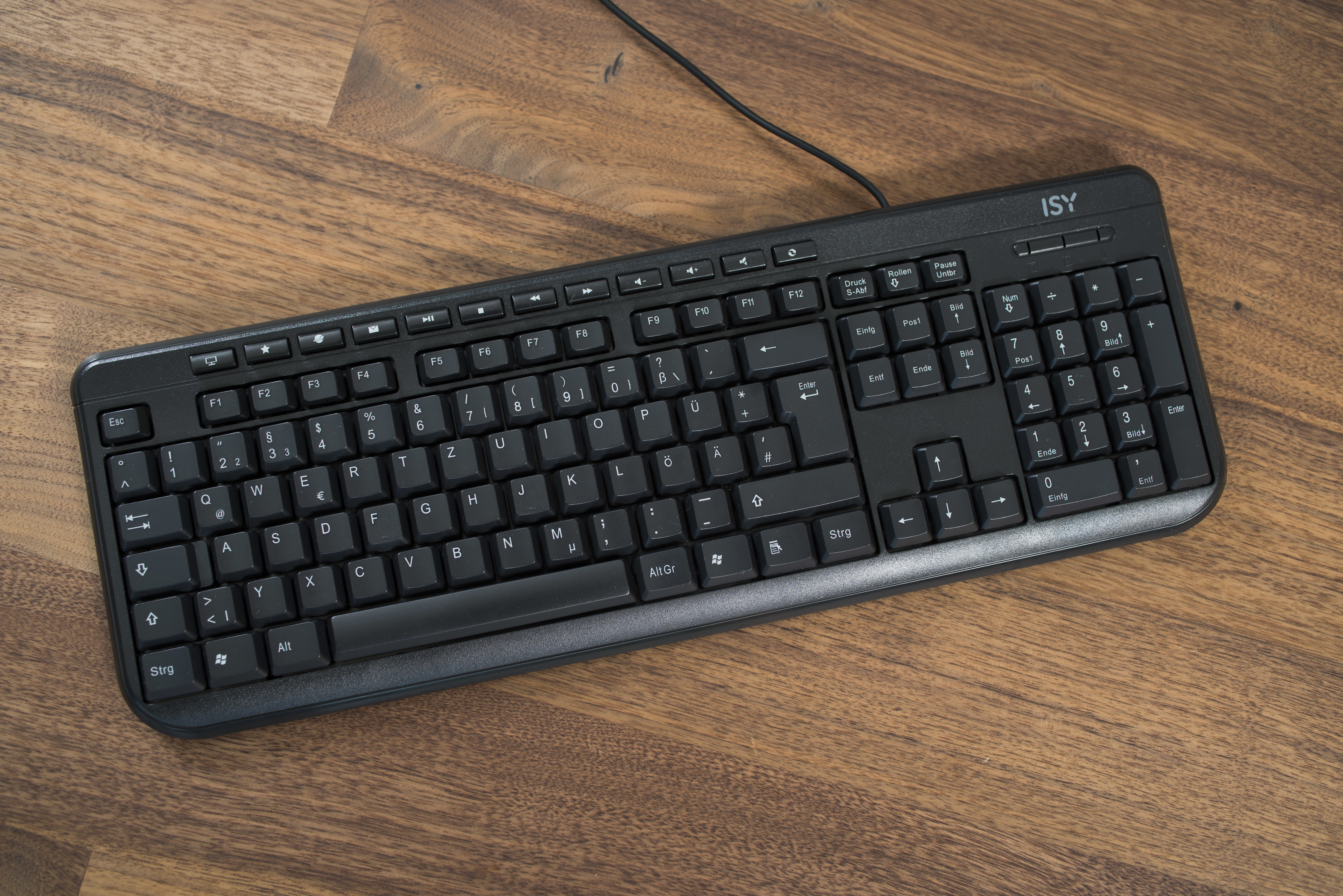 Eine schwarze Tastatur auf einem Holztisch mit Tasten und Buchstaben.