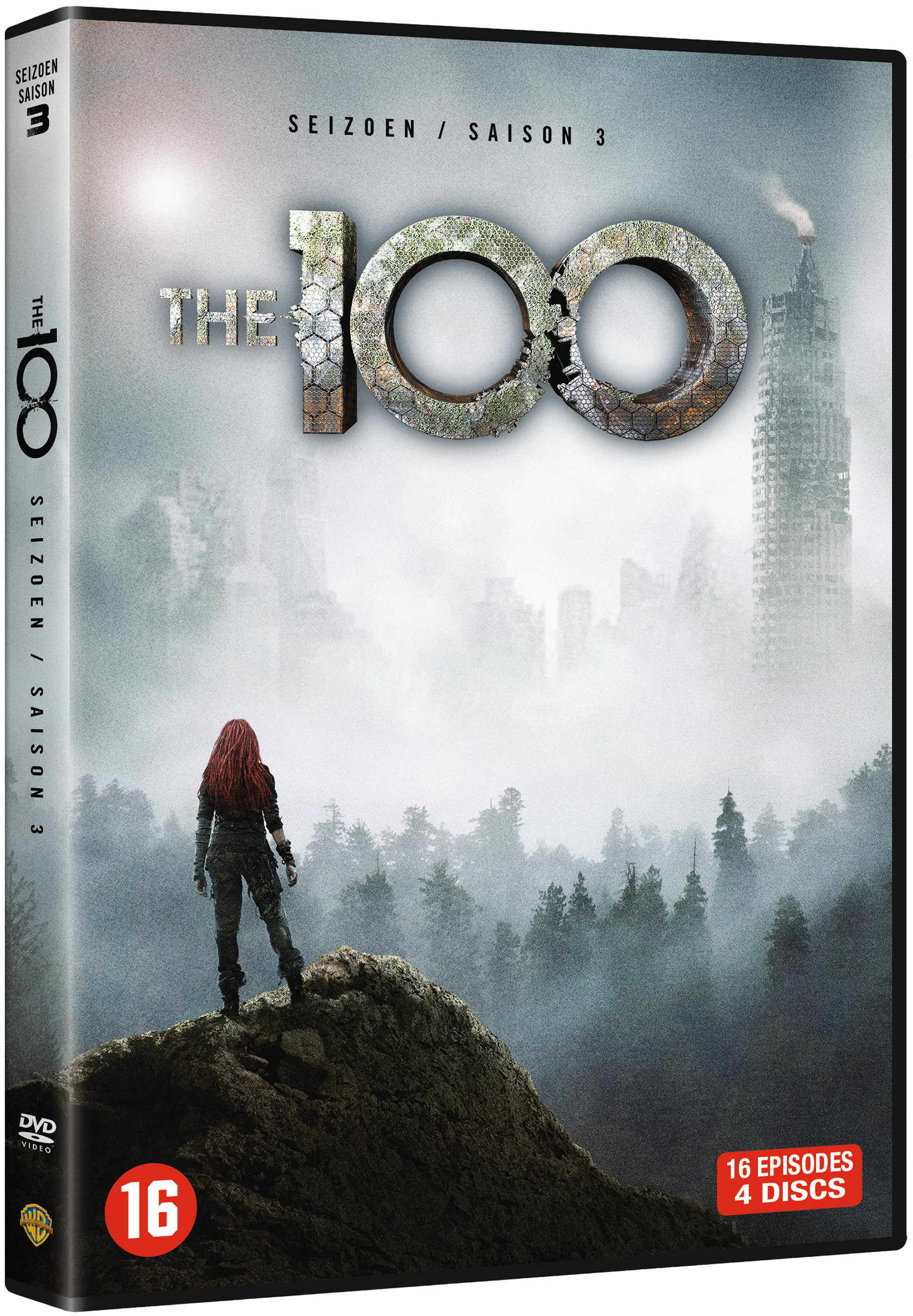 A woman with red hair stands on a rock overlooking a foggy city skyline.