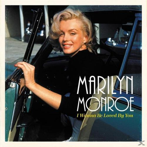 Marilyn Monroe in einem Auto. Blondes Haar, schwarzes Oberteil, lächelnd. Text 'MARILYN MONROE' und 'I Wanna Be Loved By You'.