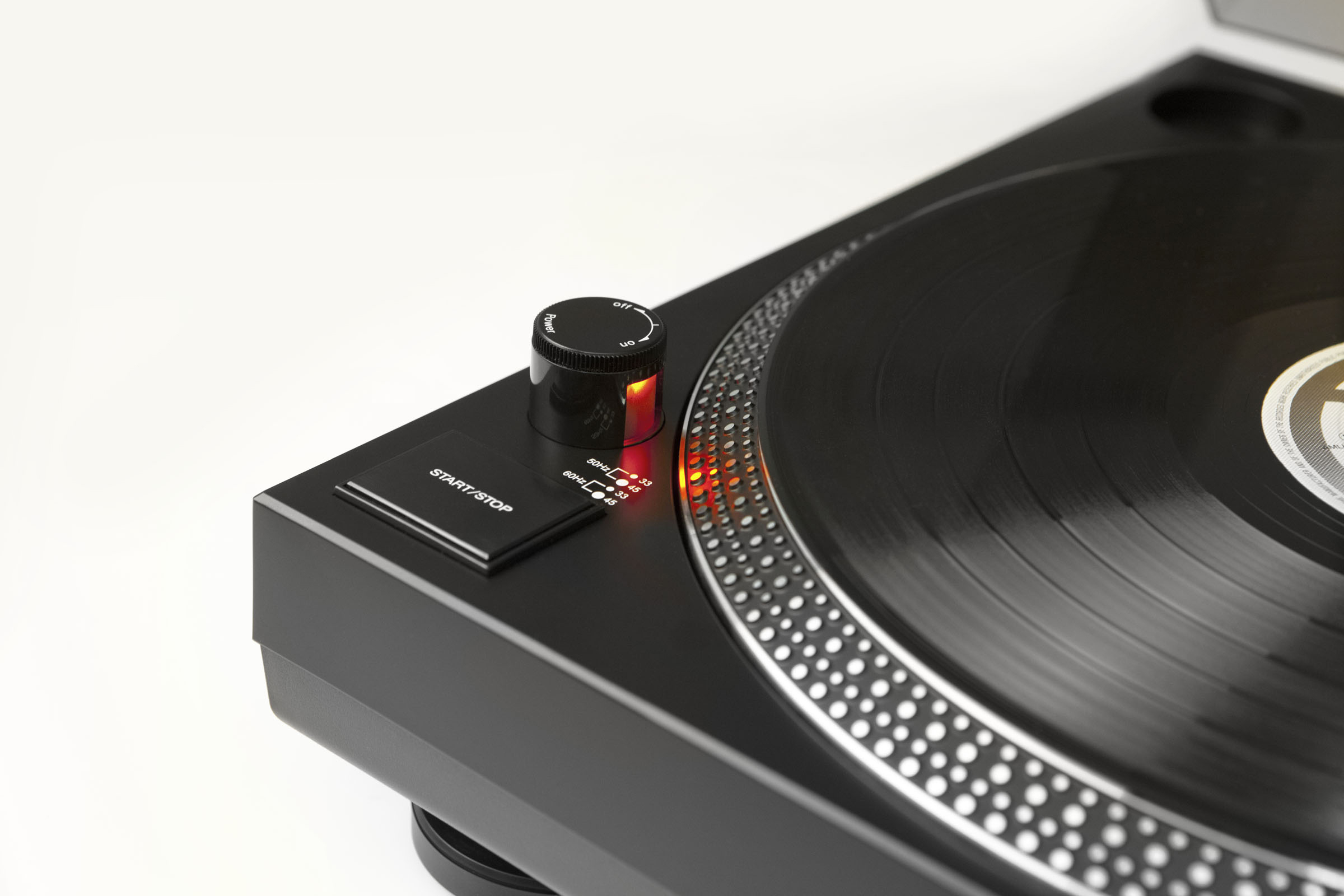 Nahaufnahme eines Plattenspielers mit einer schwarzen Vinyl-Schallplatte. Start/Stopp-Taste, Drehregler und Lichter sind sichtbar.