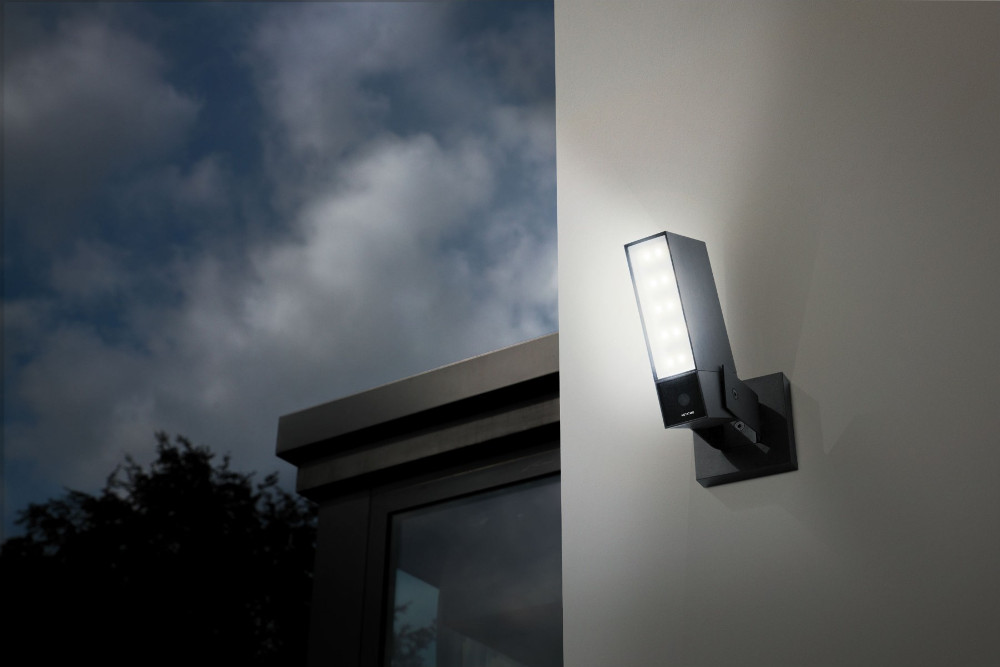 Een beveiligingscamera op een muur gemonteerd, met een helder licht dat hem verlicht.
