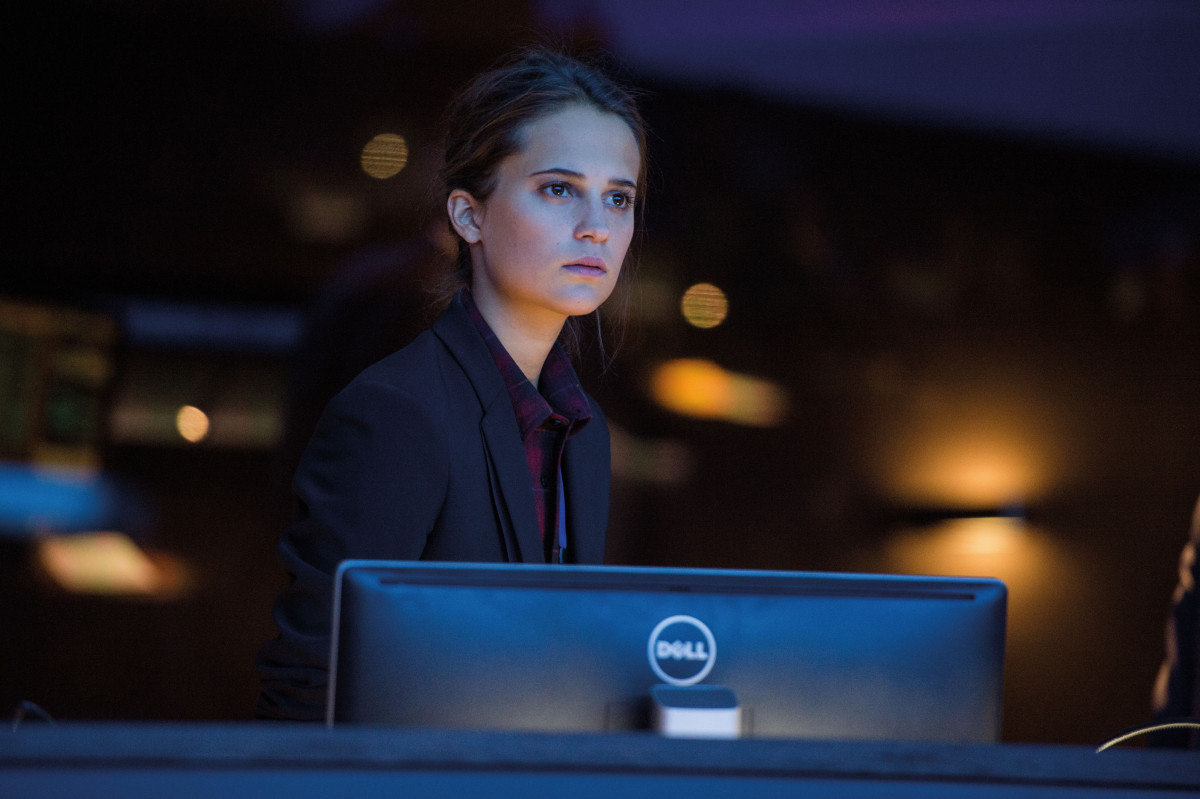 Een vrouw aan een bureau die naar een computerscherm kijkt. Ze draagt een blazer.