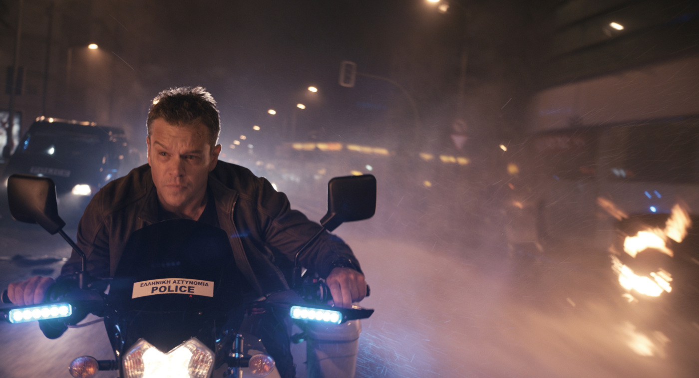 Matt Damon op een motor, nachtscène, met een politiebord op de motor.