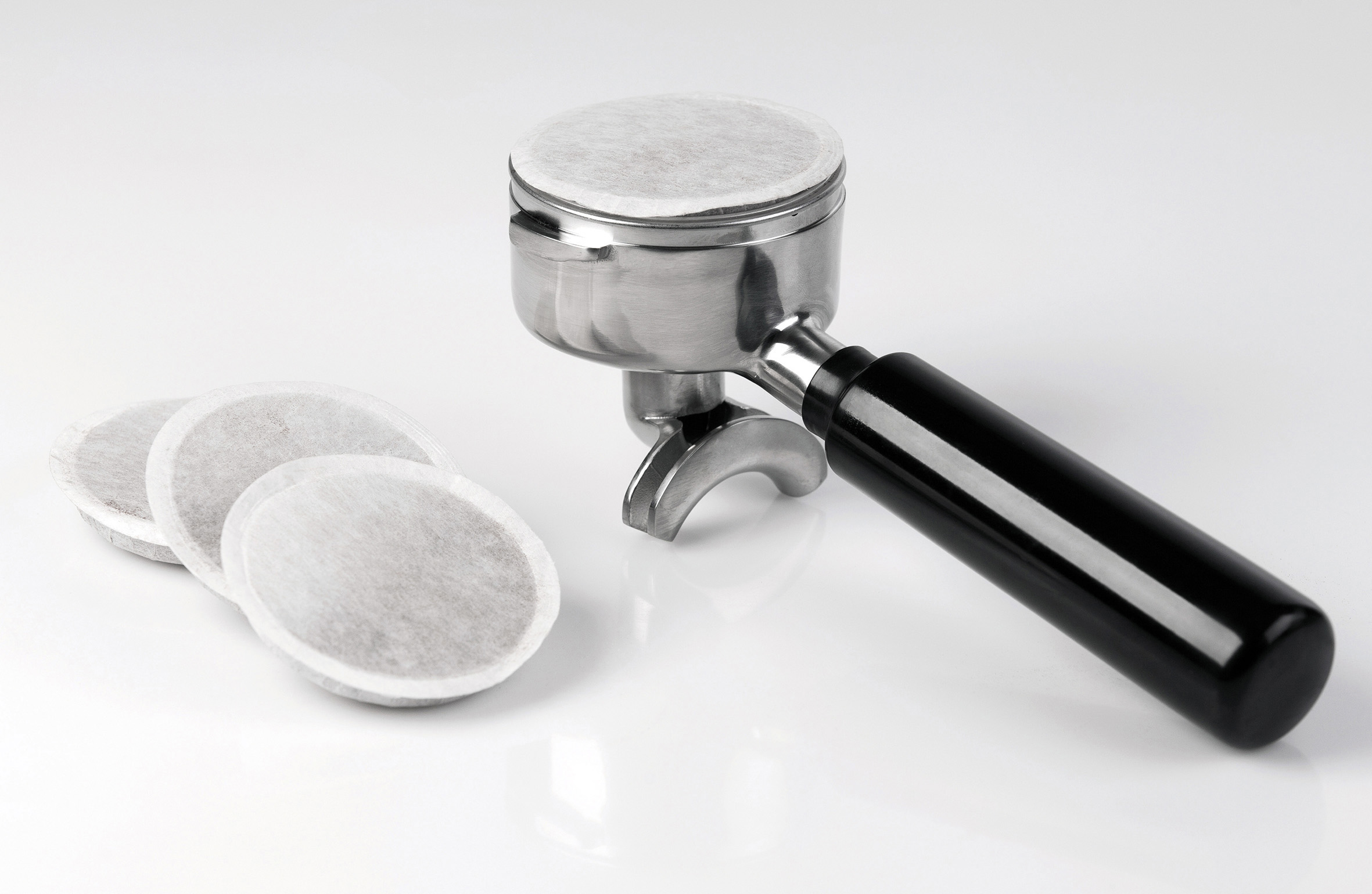 Espressomaschinen-Siebträger mit Filterpads. Schwarzer Griff, Metalloberfläche.