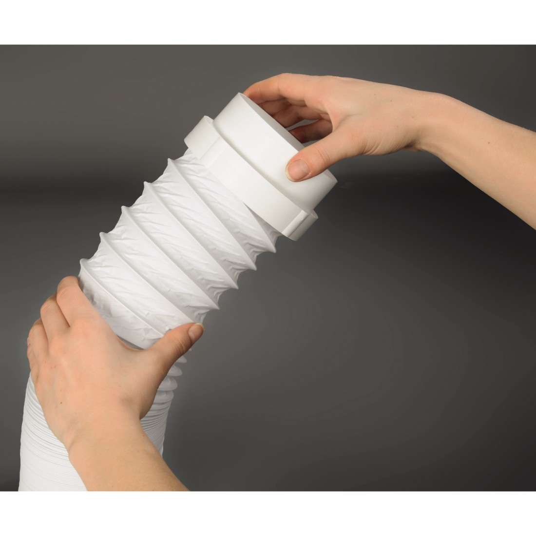 Hands holding a white, corrugated, flexible tube with white connectors. Gray background.
