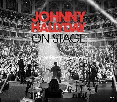Photo de concert de Johnny Hallyday sur scène, foule en arrière-plan, avec un panneau fermé.